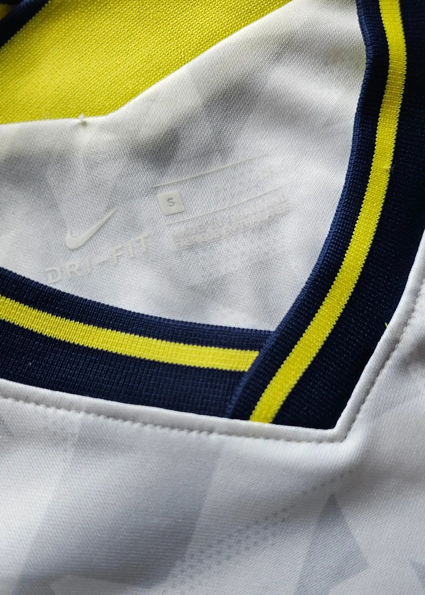 Detail view featuring DRI-FIT label and size S on the collar of a signed football shirt.