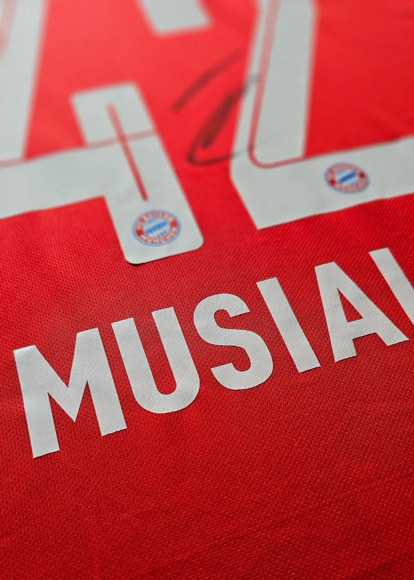Detail showing No. 42 and Musiala's signature on a red Bayern Munich football shirt.