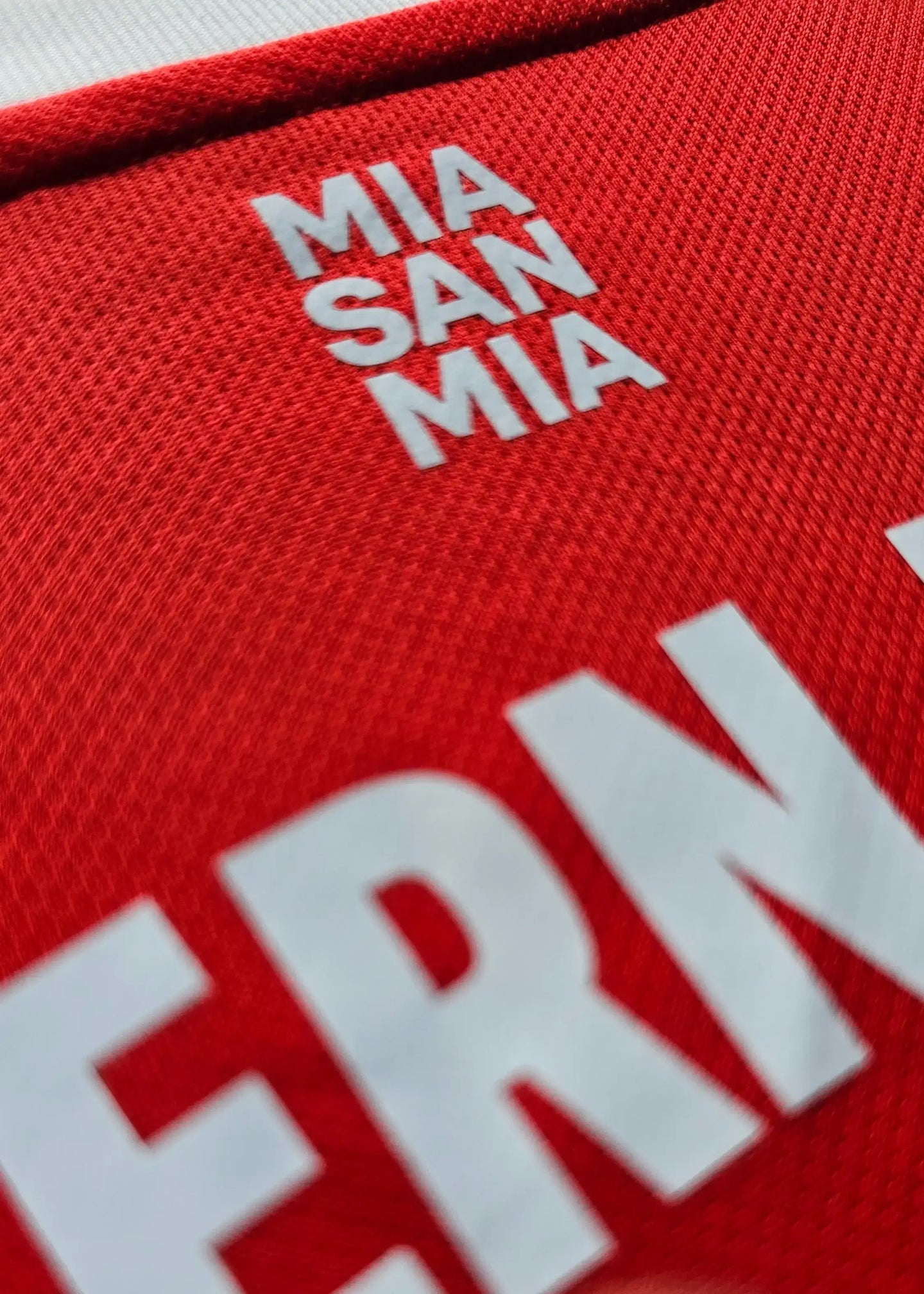 Close-up of red football shirt showing white text 'MIA SAN MIA'.