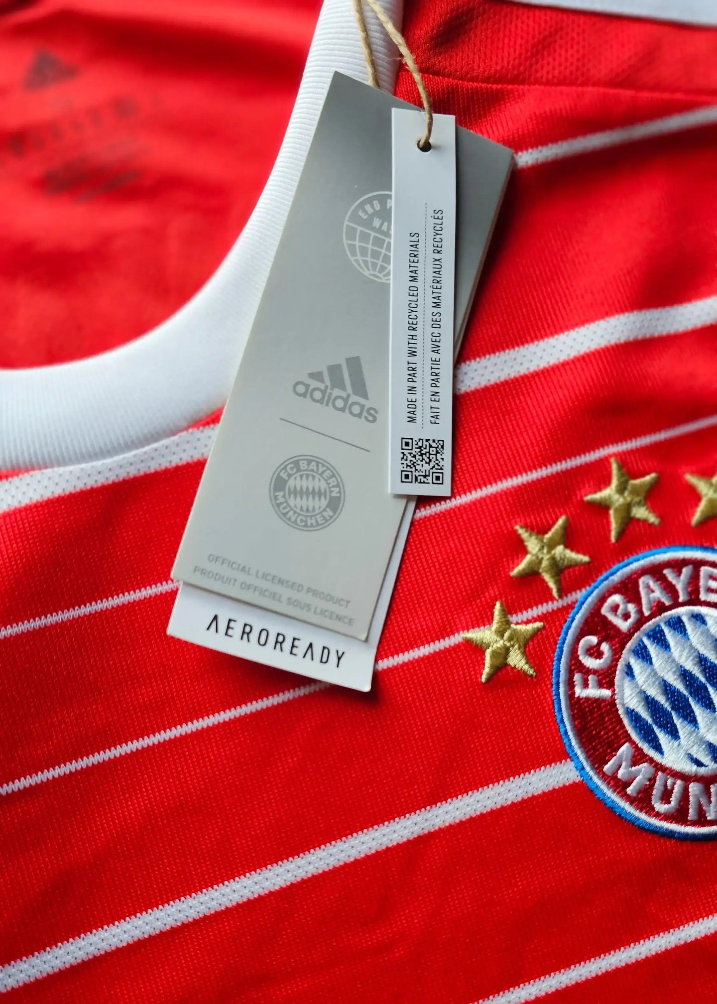 Details showing the FC Bayern Munchen crest with four stars and adidas branding on a red football shirt.