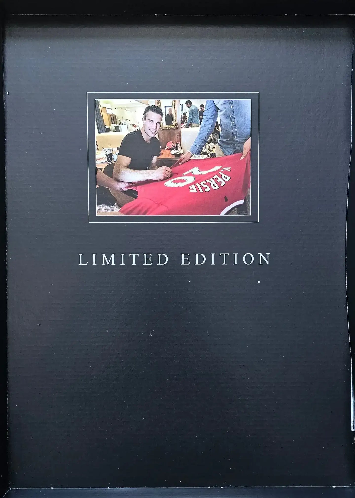 Robin van Persie signing a Manchester United football shirt displaying No. 20, labeled Limited Edition.