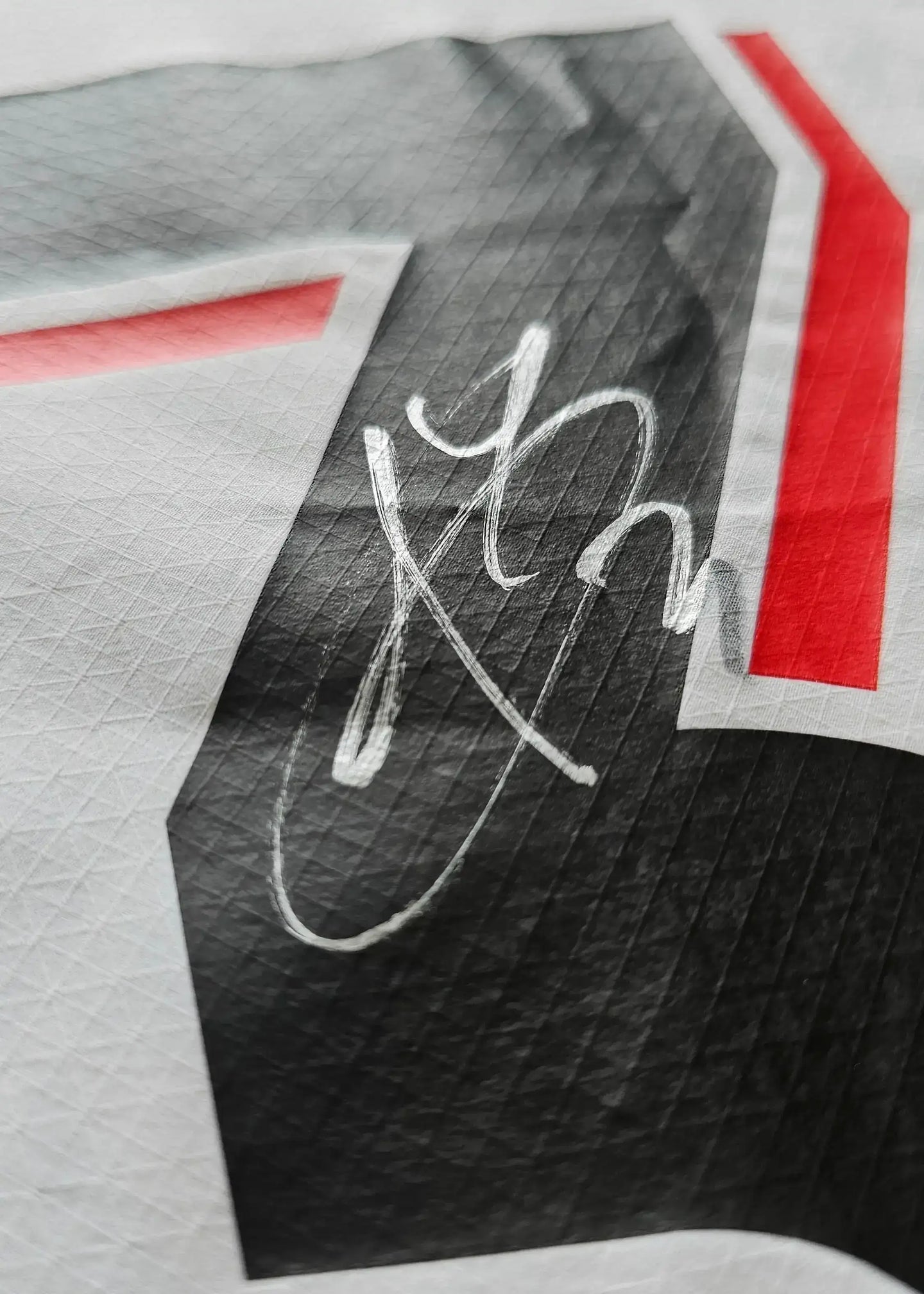 Close-up showing the signature of Yarek Gasiorowski on the black and red football shirt.