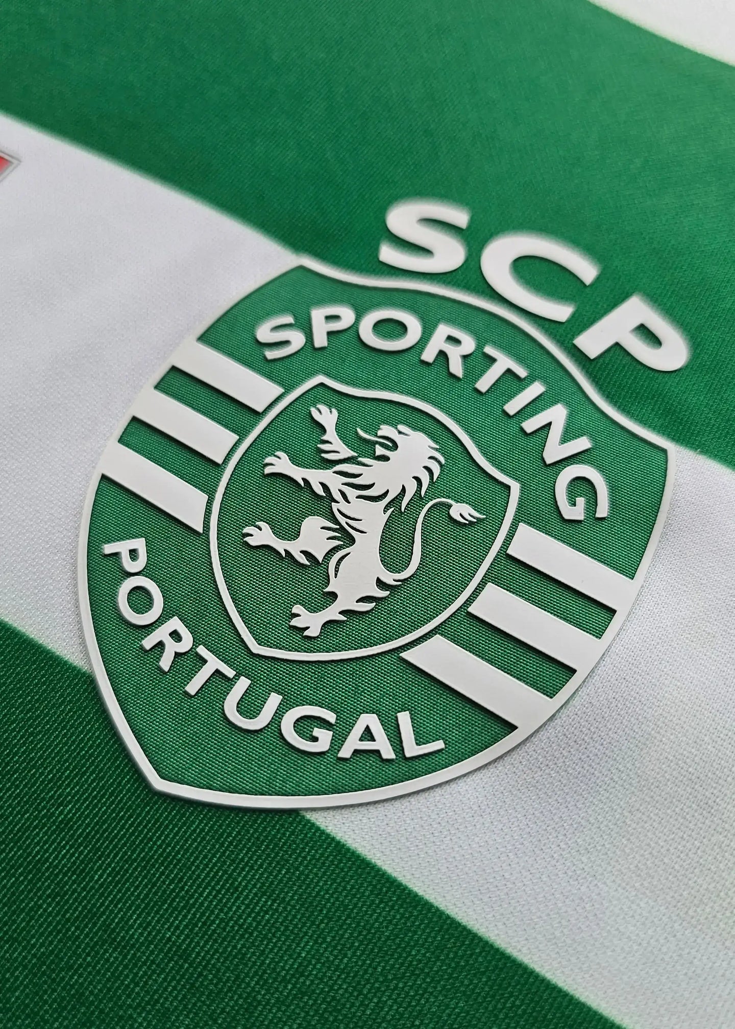 Green and white striped Sporting CP crest featuring a lion and the text SCP PORTUGAL.