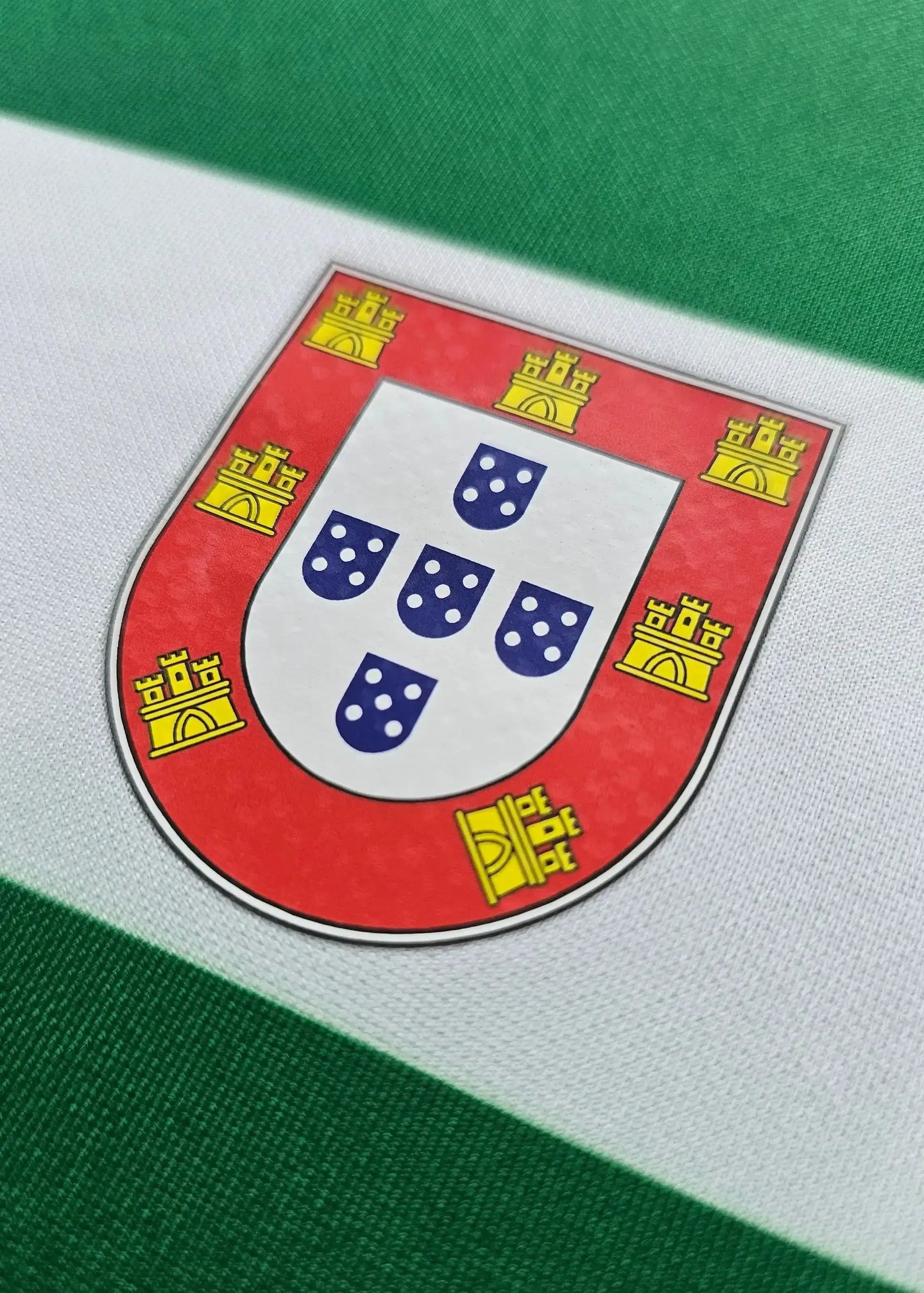 Crest detail of Sporting CP football shirt featuring the Portuguese coat of arms with blue shields.