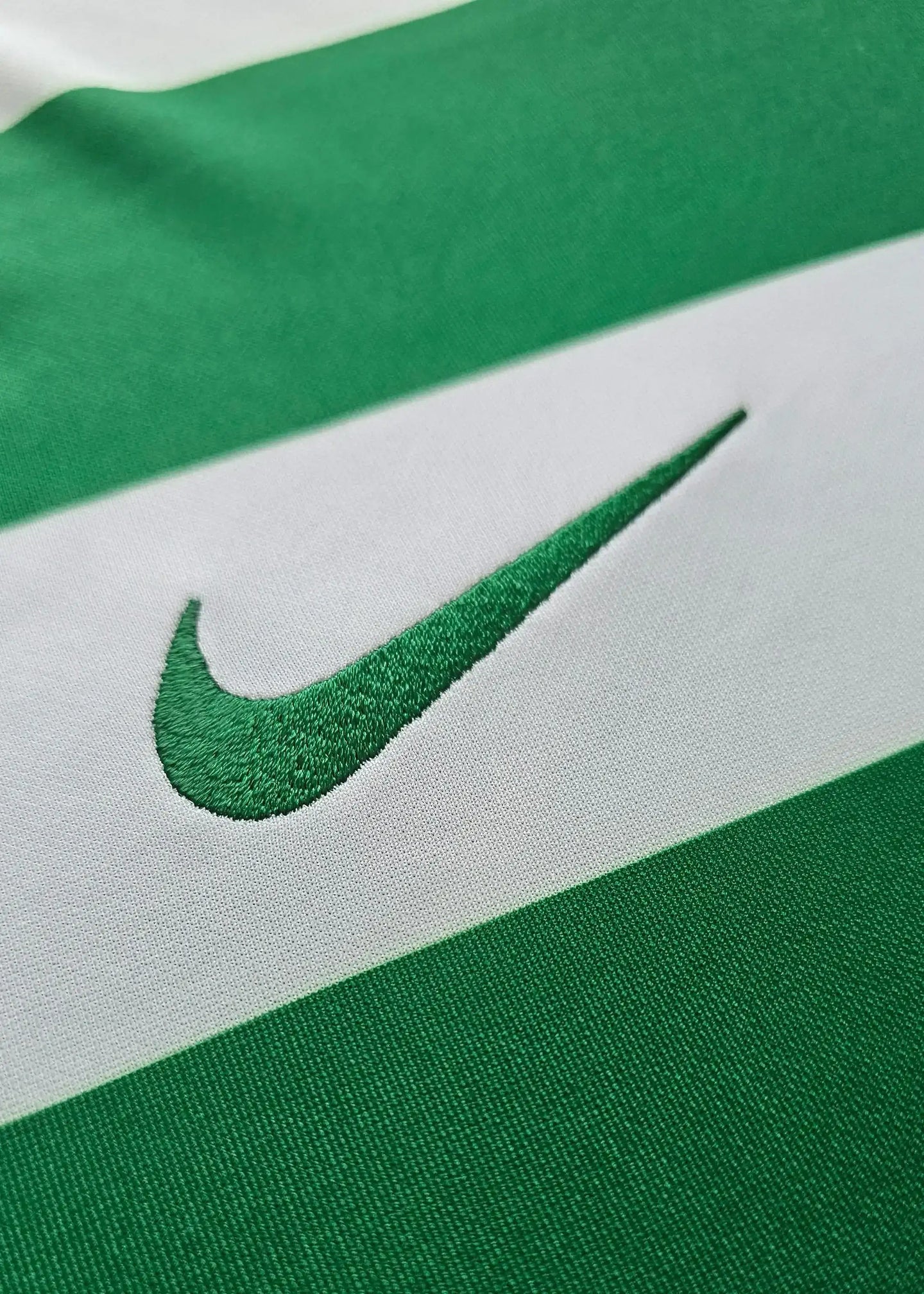 Close-up of the green and white striped Sporting CP football shirt featuring the Nike logo.
