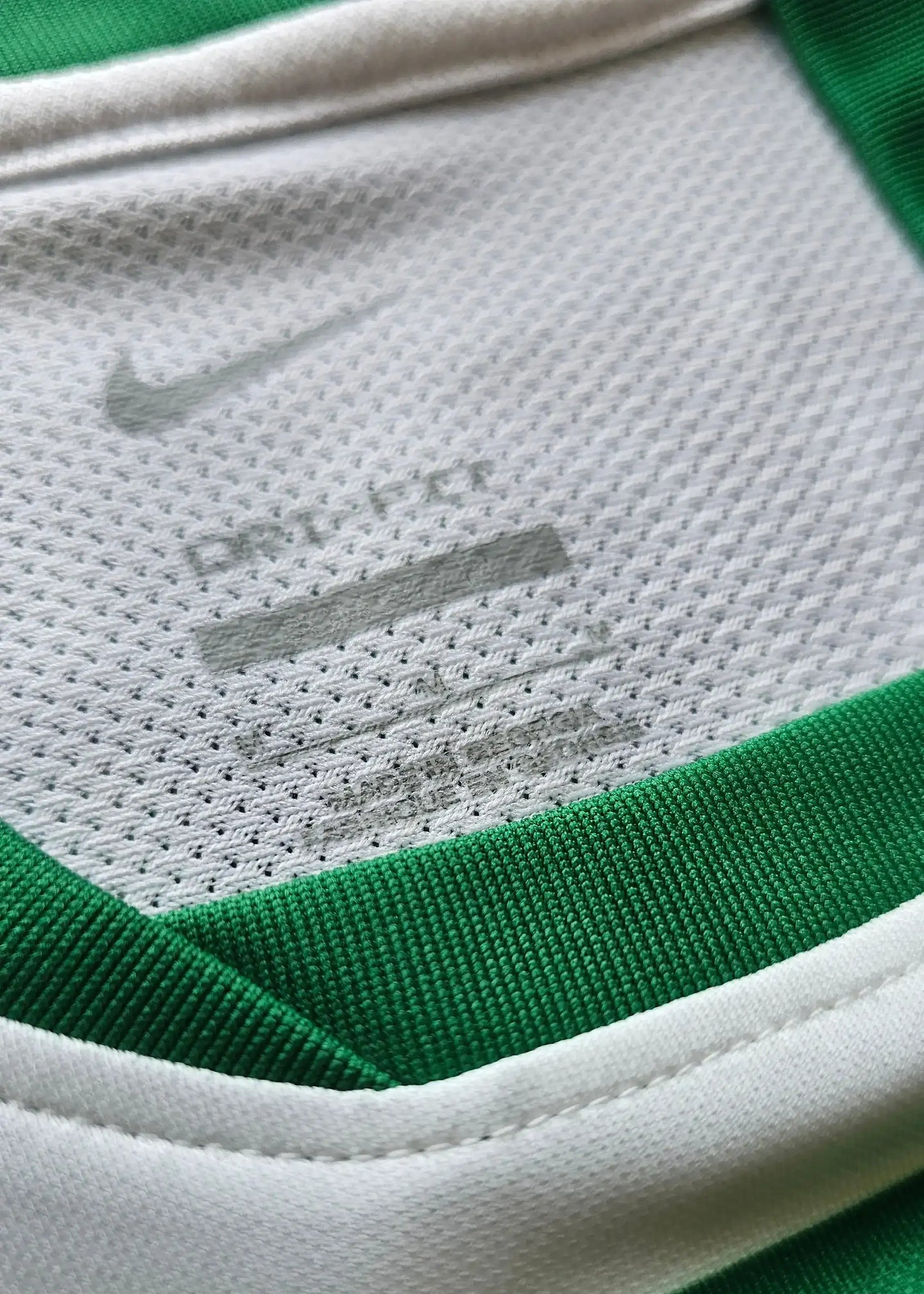 Nike Dri-FIT technology label on the inside collar of a green and white Sporting CP shirt.
