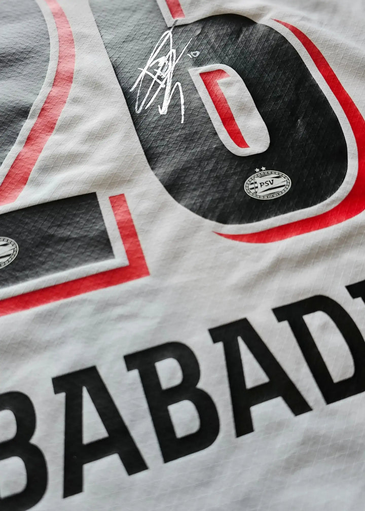 Signature on the back of the Isaac Babadi 26 PSV football shirt with red and white design.