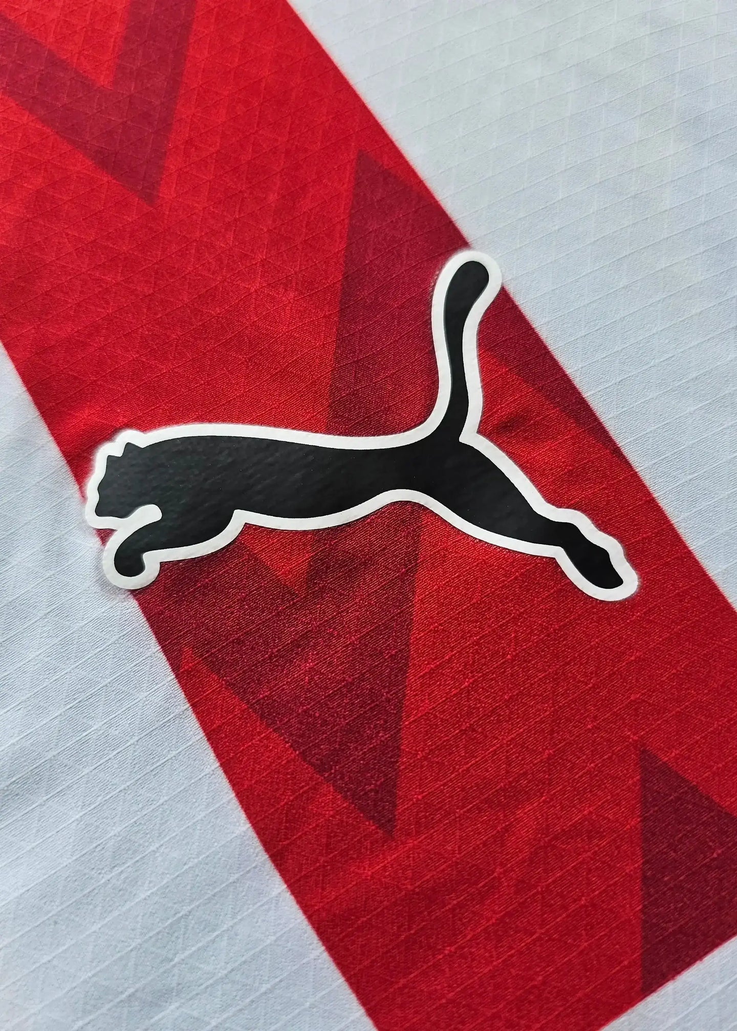 Close-up of the black Puma logo on a red and white PSV football shirt.