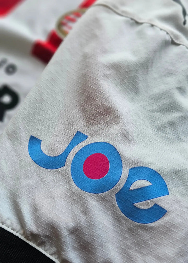 White sleeve detail showing the blue and pink 'Joe' sponsor logo.