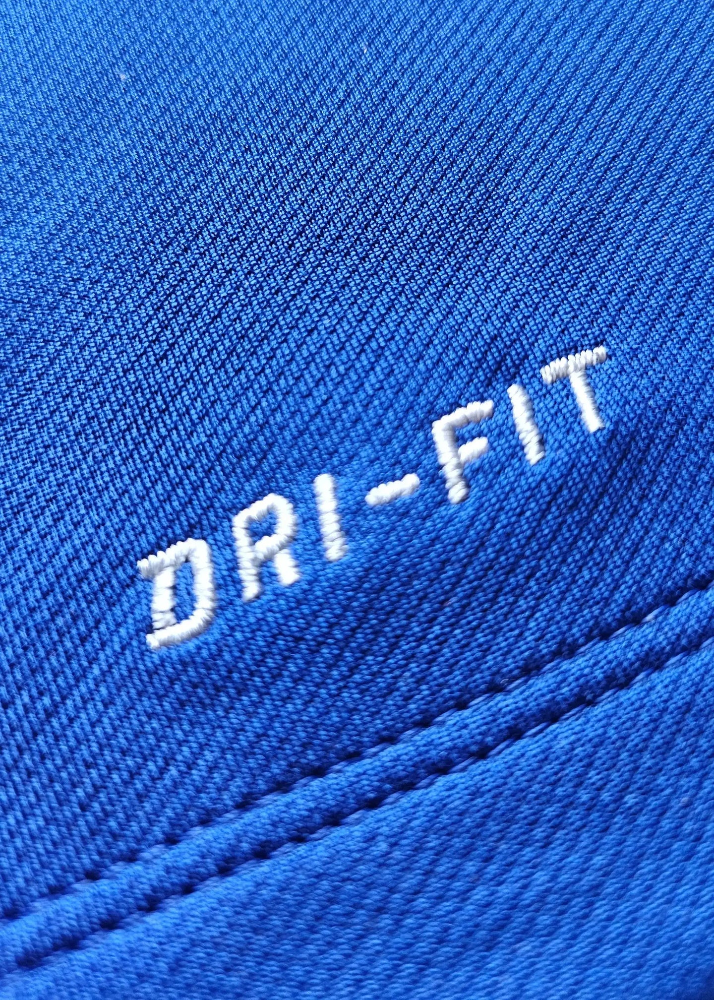 Close-up of blue fabric featuring "DRI-FIT" text embroidered in white.