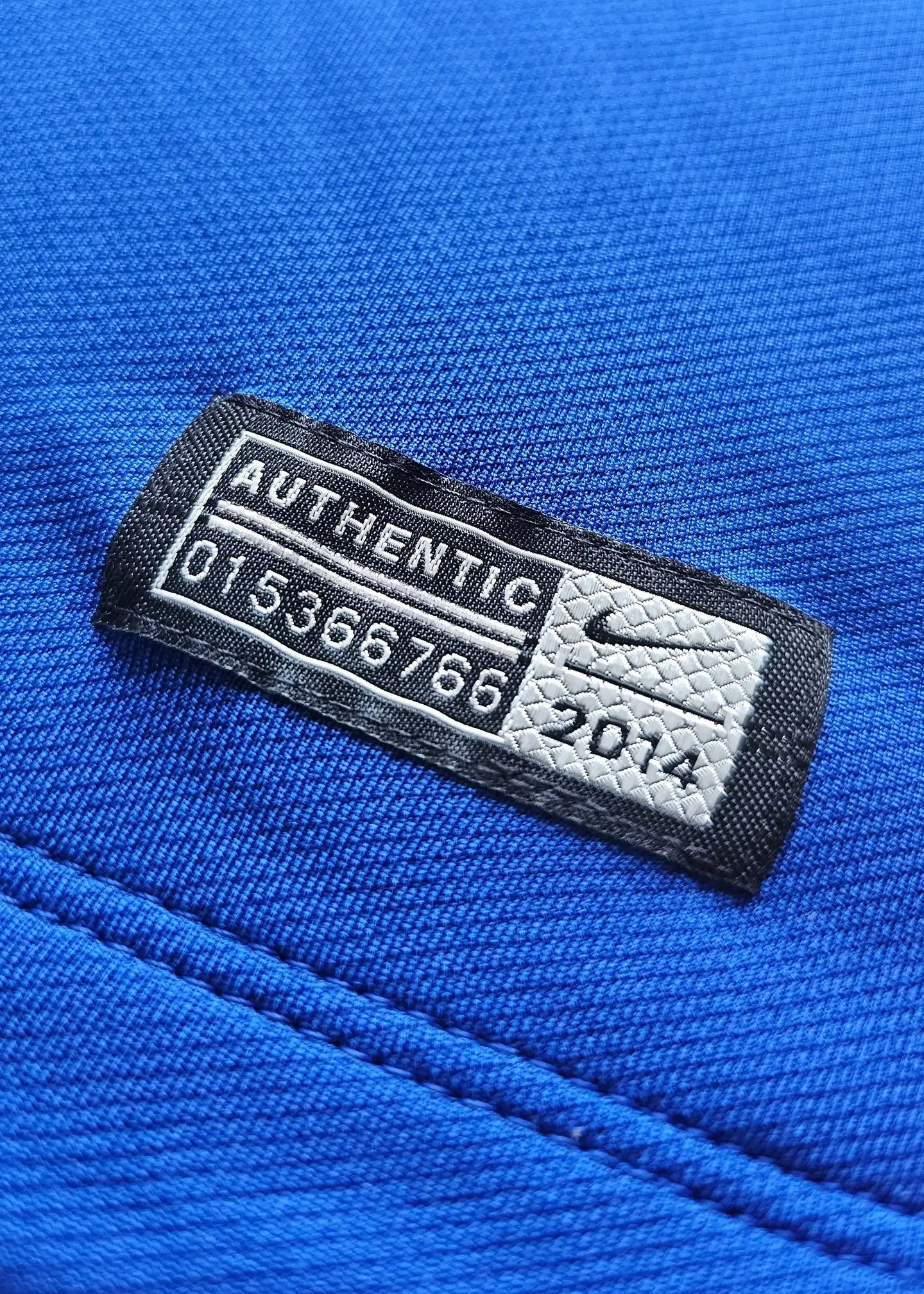 Authentic tag featuring 'AUTHENTIC', numbers '01536766', and Nike logo on blue surface.