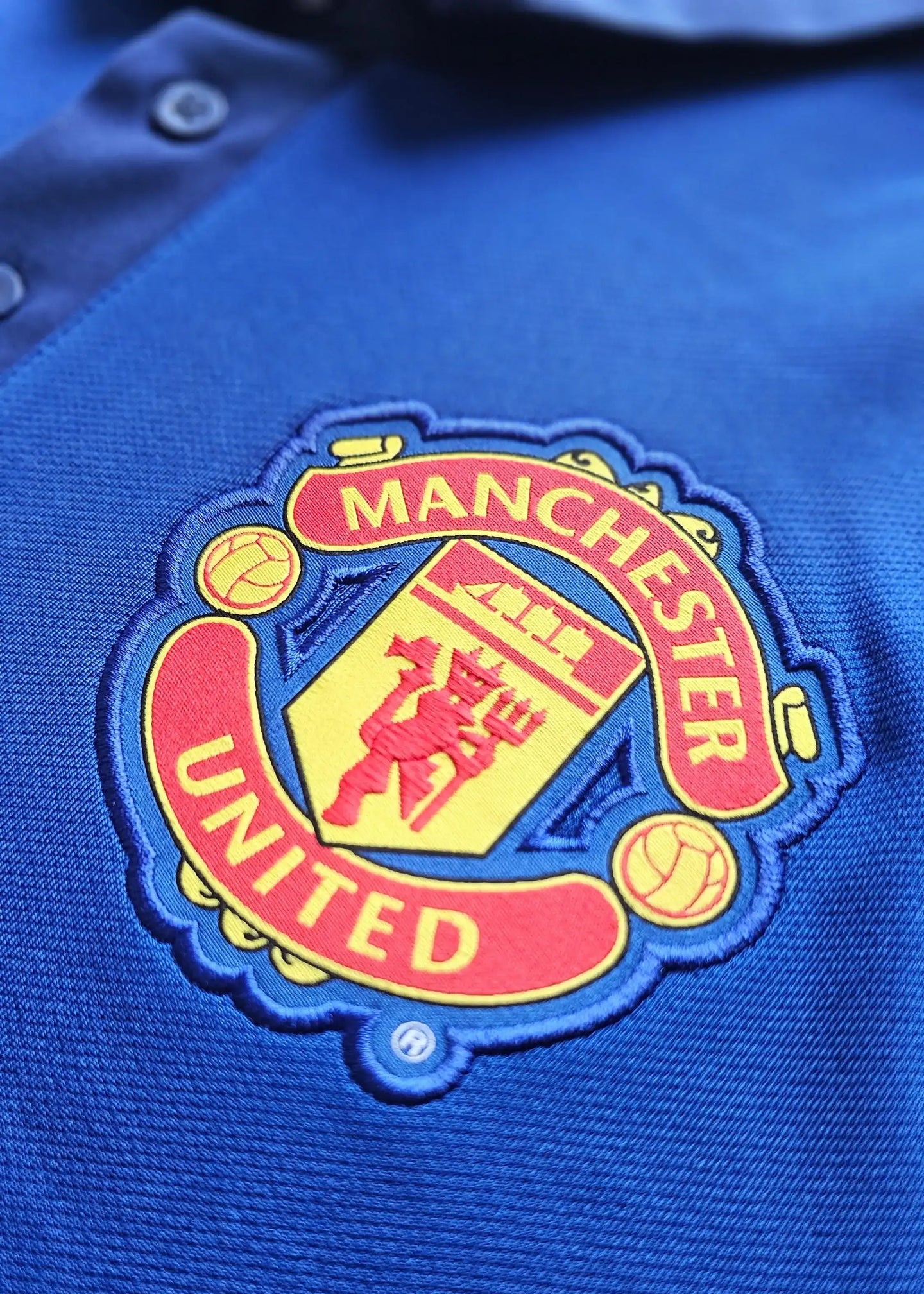 Close-up of Manchester United crest featuring "MANCHESTER" and "UNITED" in vibrant colors.