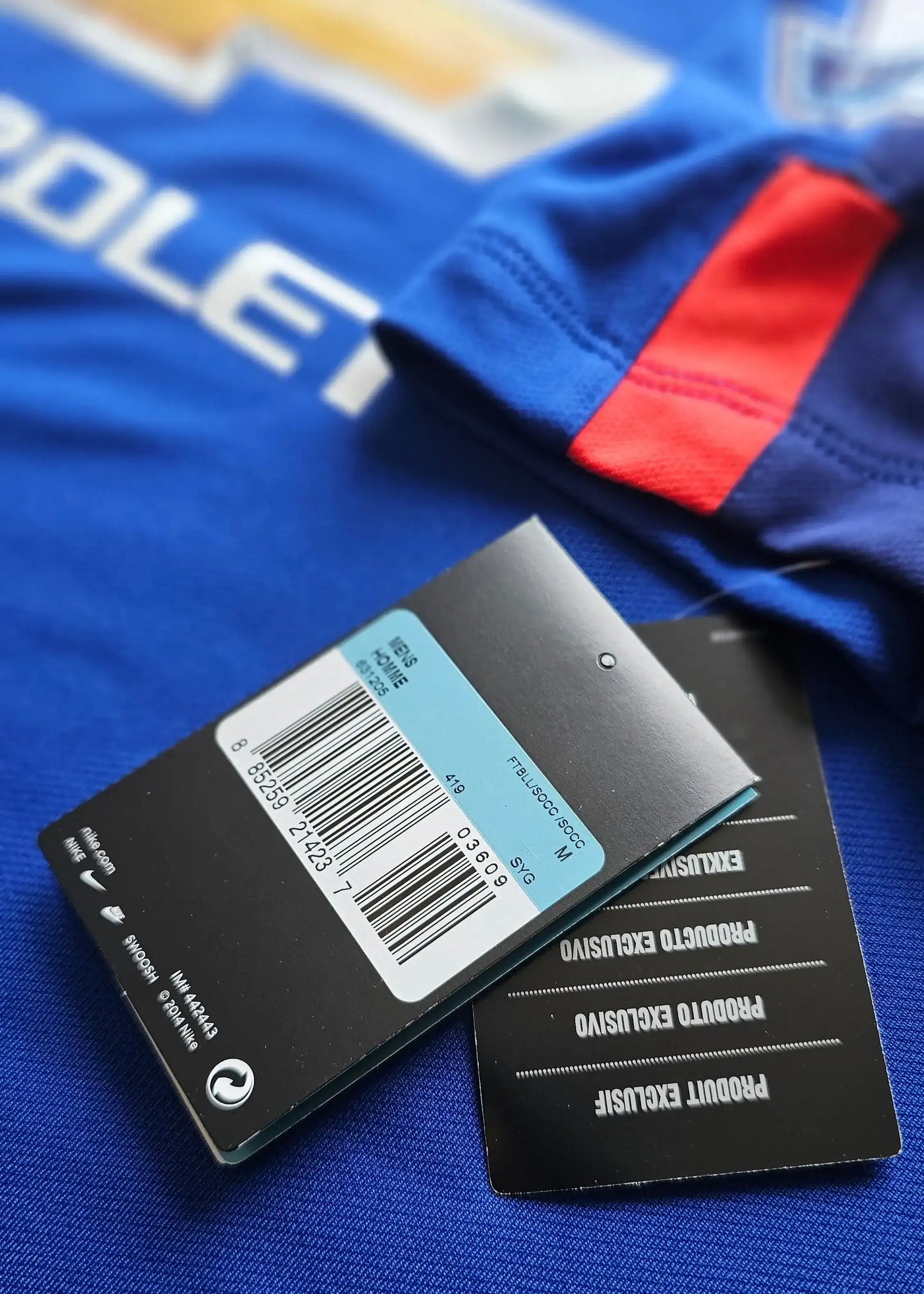 Detail view of tags and size label showing limited edition details, with blue fabric and red sleeve accent.