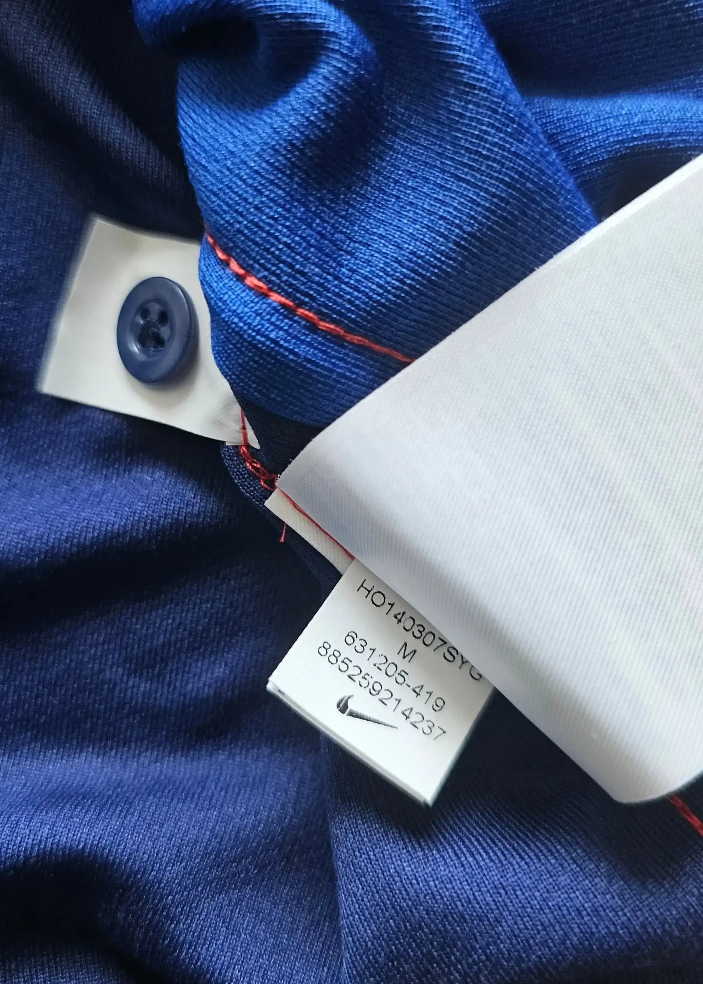 Detail view showing care label with size M and Nike logo on the Robin van Persie signed blue football shirt.