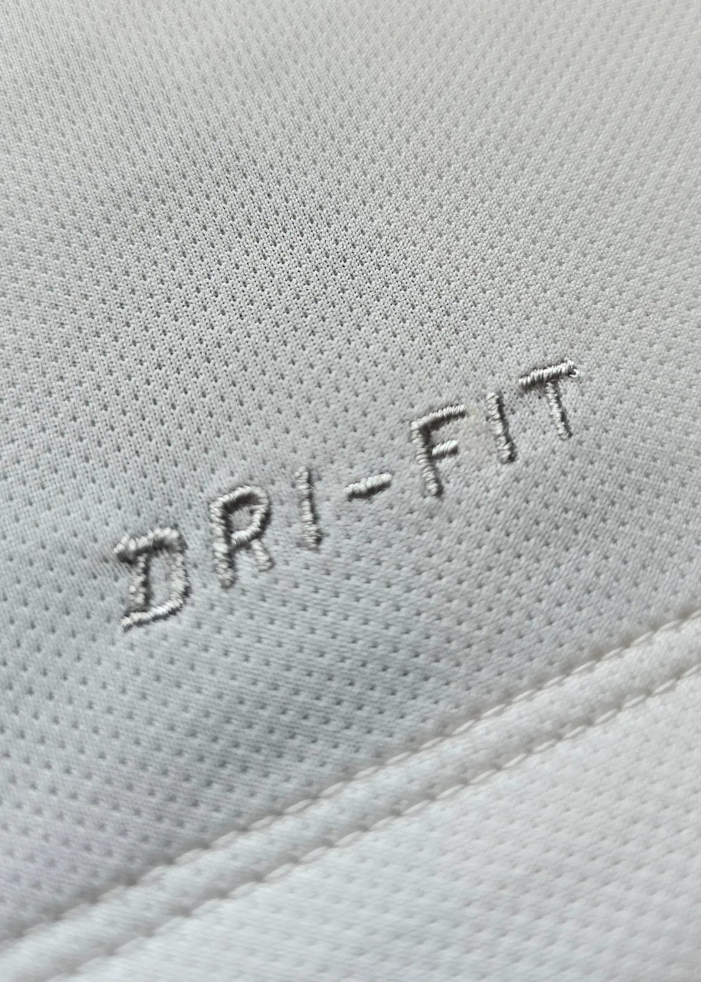 Close-up detail of white fabric featuring 'DRI-FIT' embroidery.
