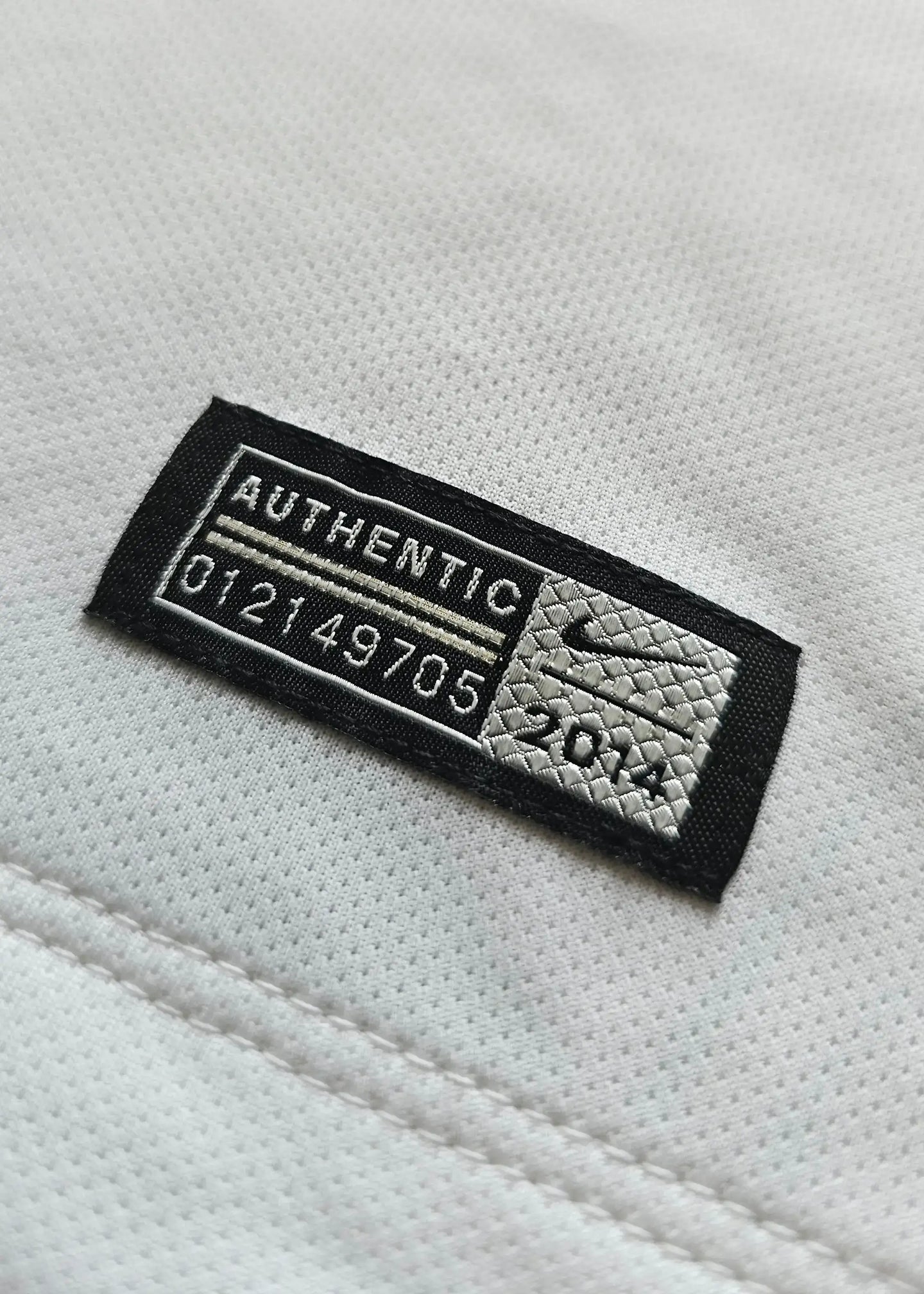 Close-up of authenticity label showing 'AUTHENTIC 012149705' and 'Nike' on white fabric.