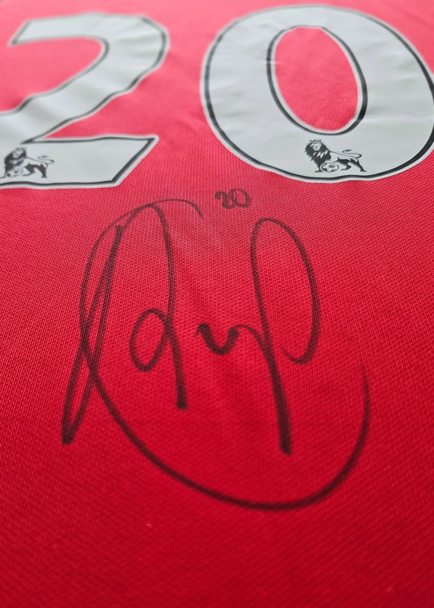 Shirt detail featuring No. 20 and Robin van Persie's signature on a red Manchester United shirt.