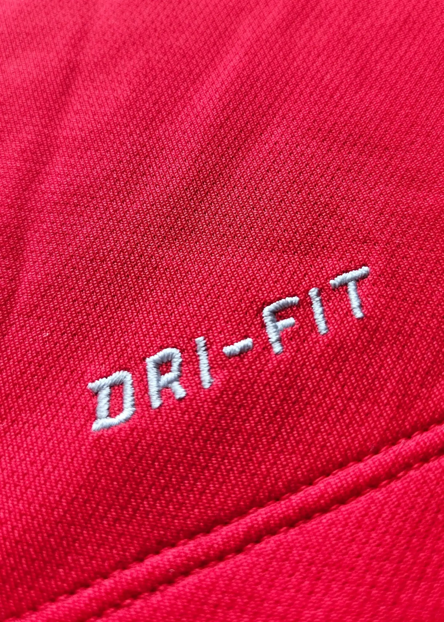 Close-up of red fabric with white DRI-FIT text on a Manchester United shirt.