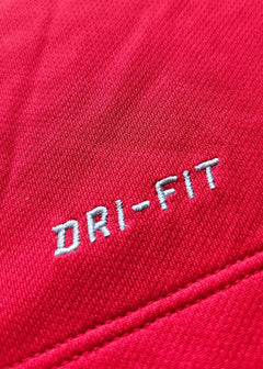 Close-up of red fabric with white DRI-FIT text on a Manchester United shirt.