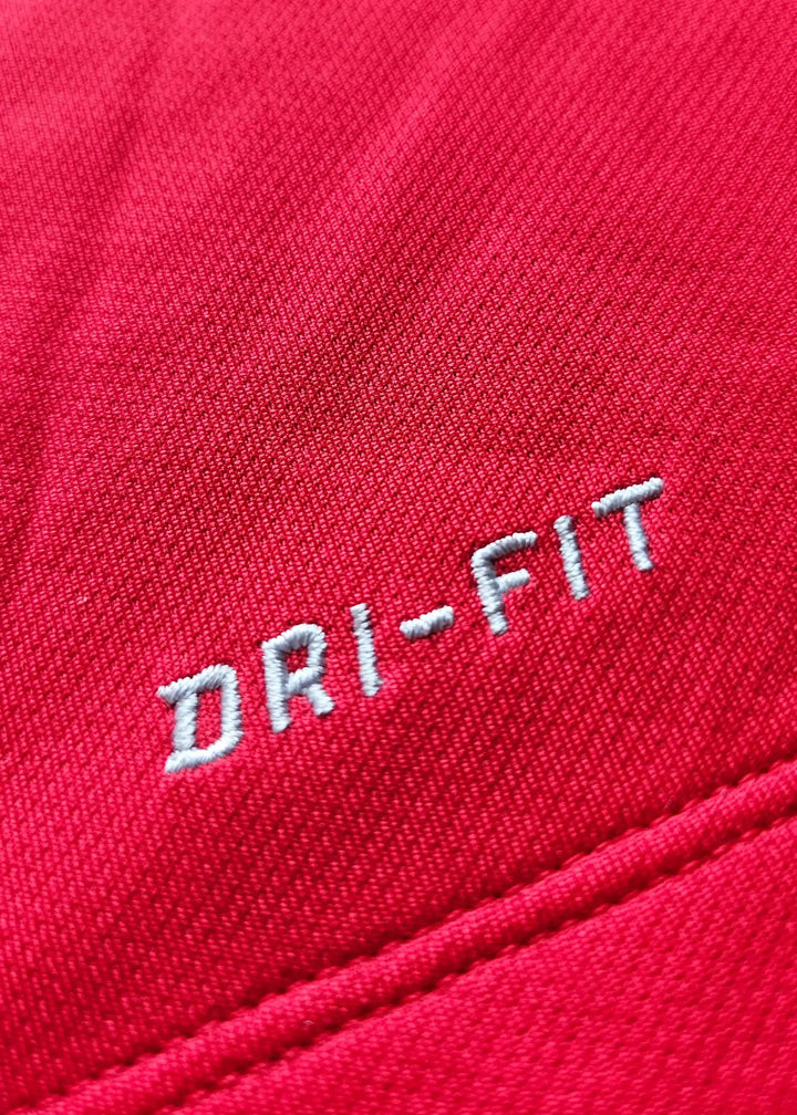 Close-up of red fabric with white DRI-FIT text on a Manchester United shirt.