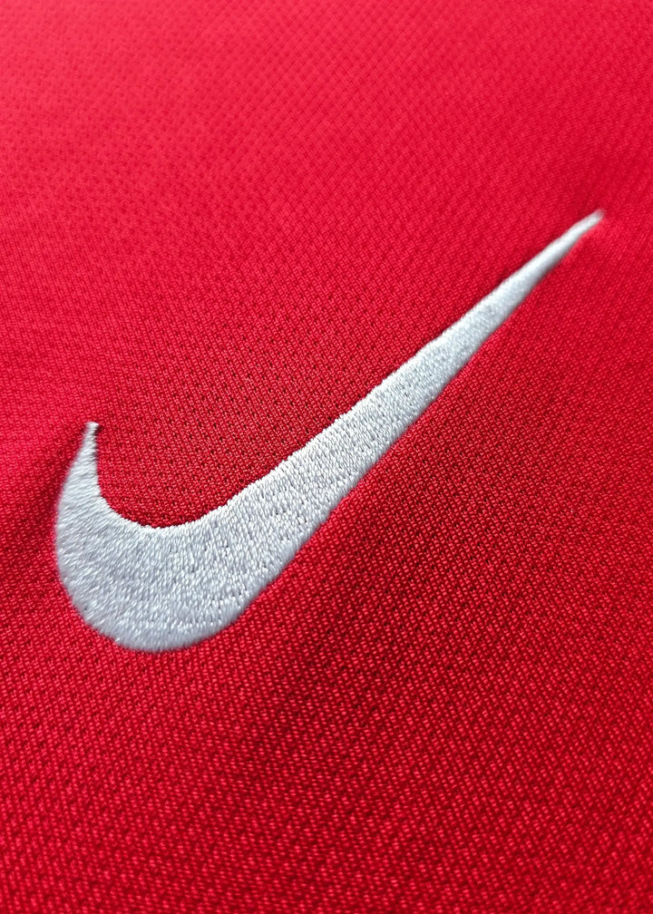 Close-up of the white Nike logo embroidered on a red shirt.