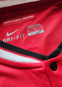 Red Nike Dri-FIT shirt with label 'YOUTH COURAGE GREATNESS' and care information.