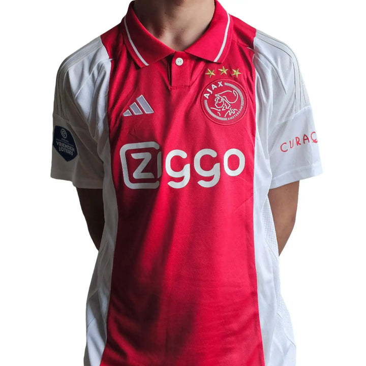 Front view of red Ajax football shirt featuring Ziggo logo, three stars, and UEFA patch.