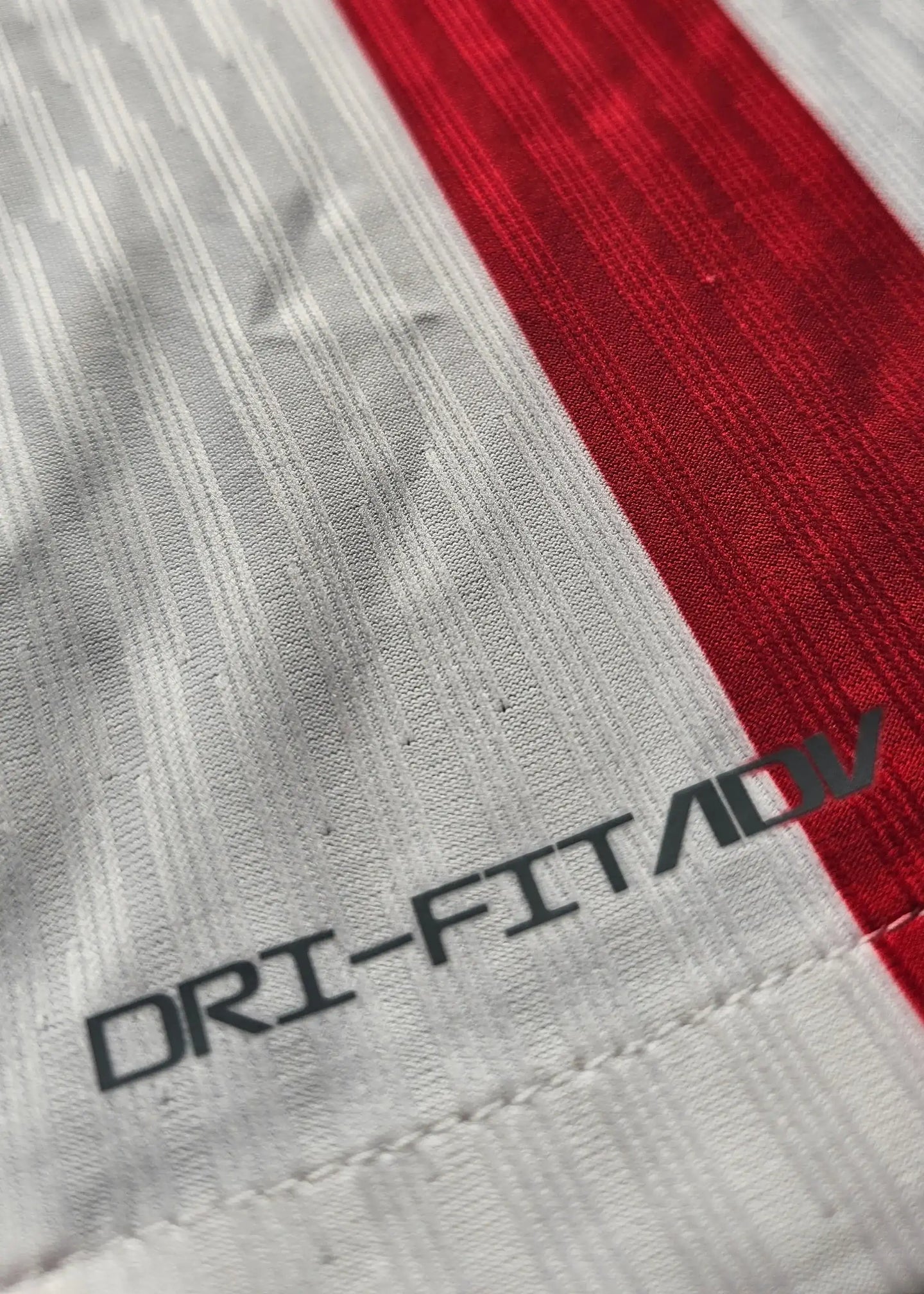 Close-up of DRI-FIT ADV text on a red and white striped Atlético Madrid shirt.