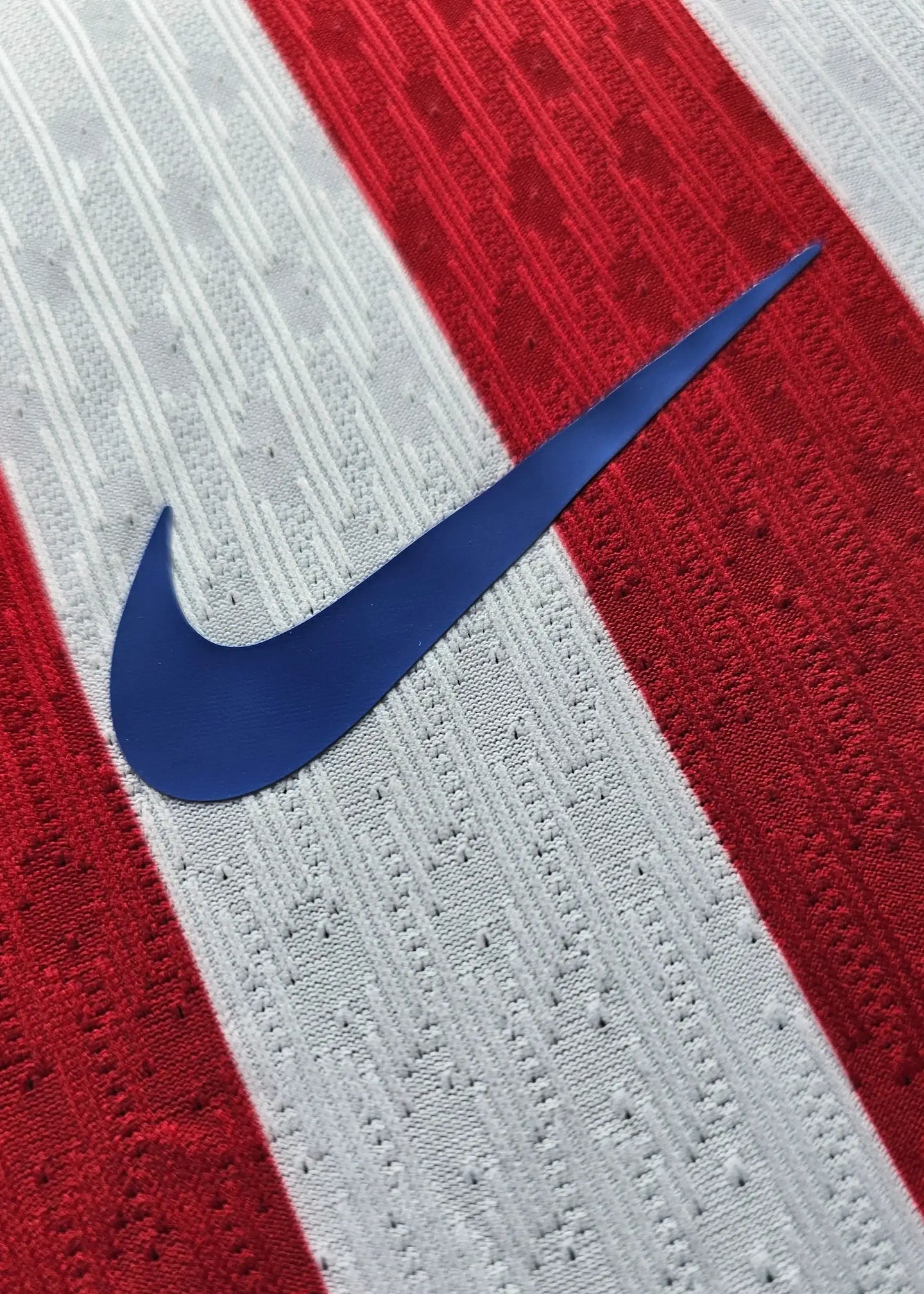 Detail of red, white striped fabric featuring a blue Nike swoosh logo.