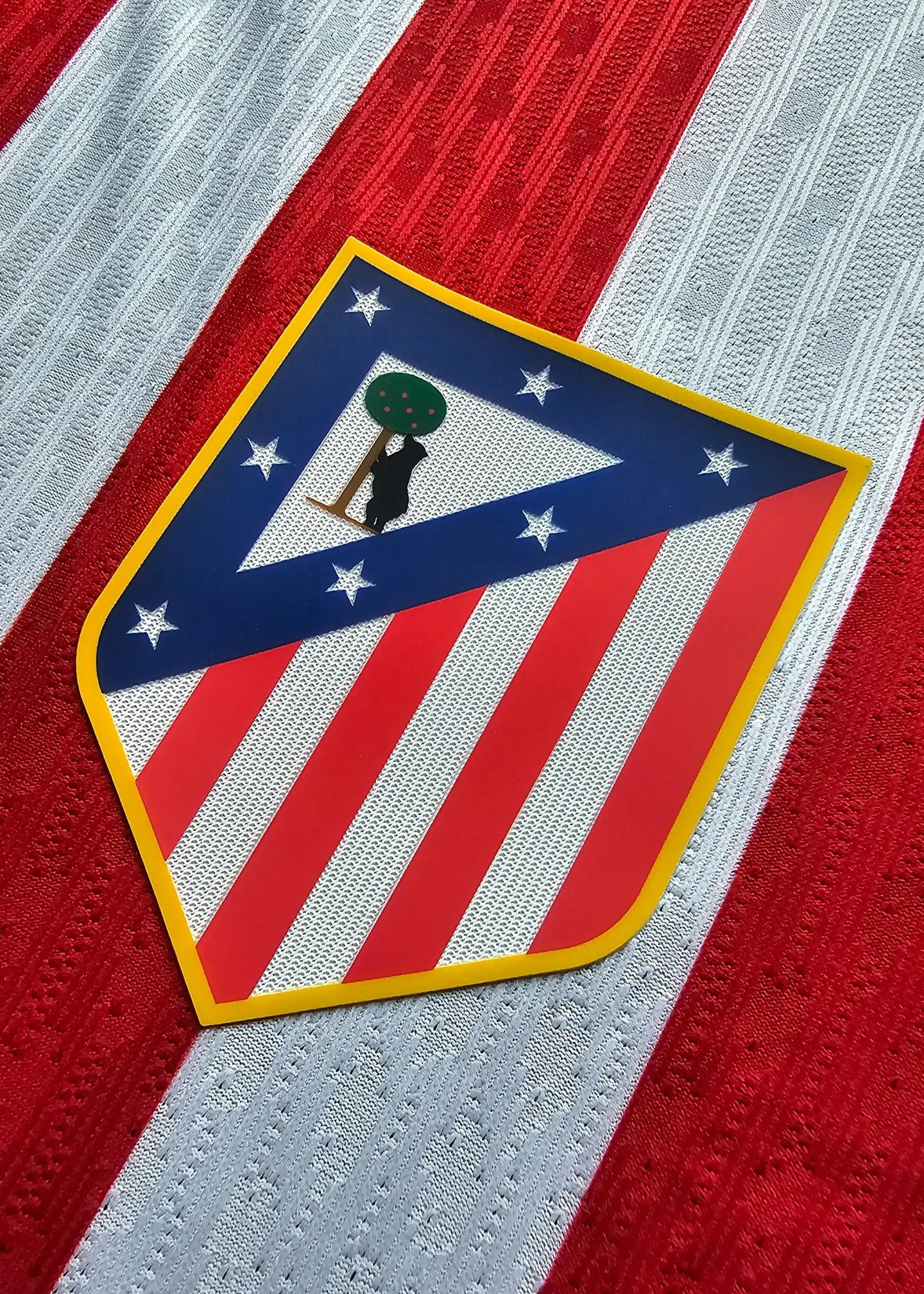 Atlético Madrid crest featuring red and white stripes, stars, and a bear holding a tree.