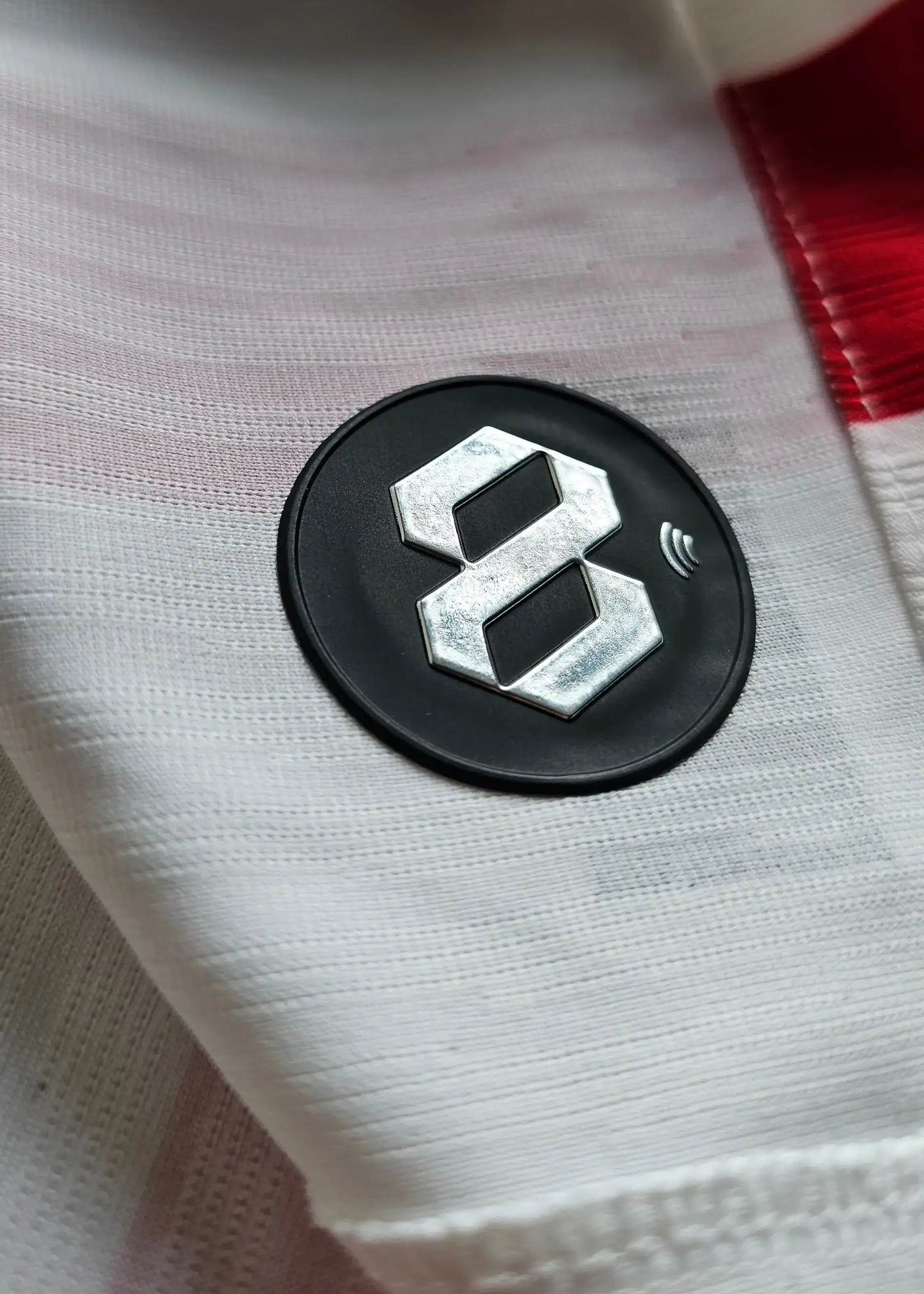 Close-up detail of the black patch with a metallic No. 28 on a white Atlético Madrid shirt.