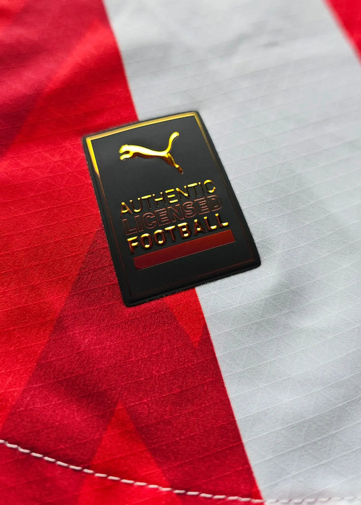 Puma Authentic Licensed Football tag on red and white striped fabric.