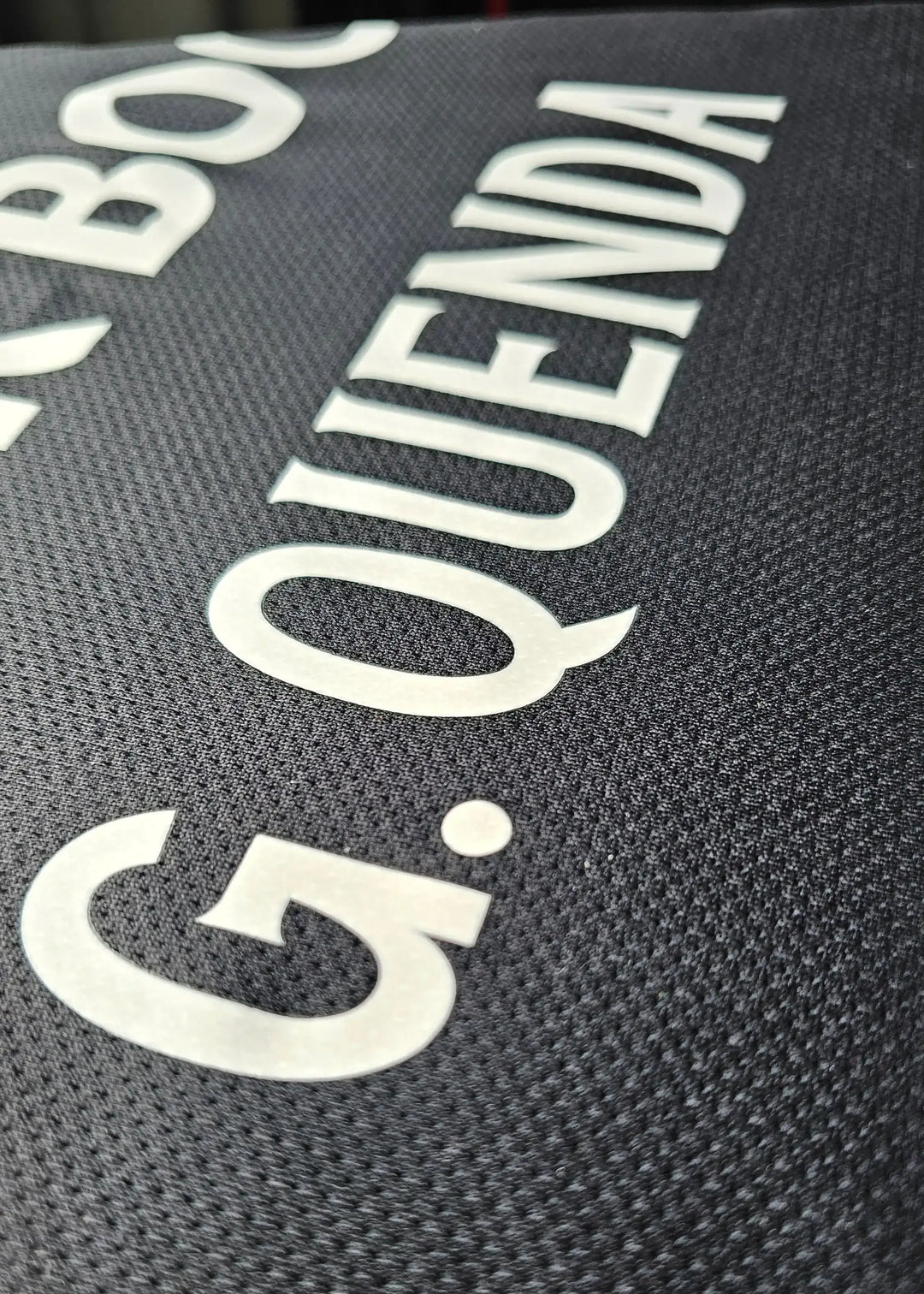 Detail of the name 'G. QUENDA' on a black Sporting CP match-worn shirt.
