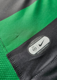 Close-up of the Nike logo and Sporting CP crest on a green and black striped match-worn shirt.
