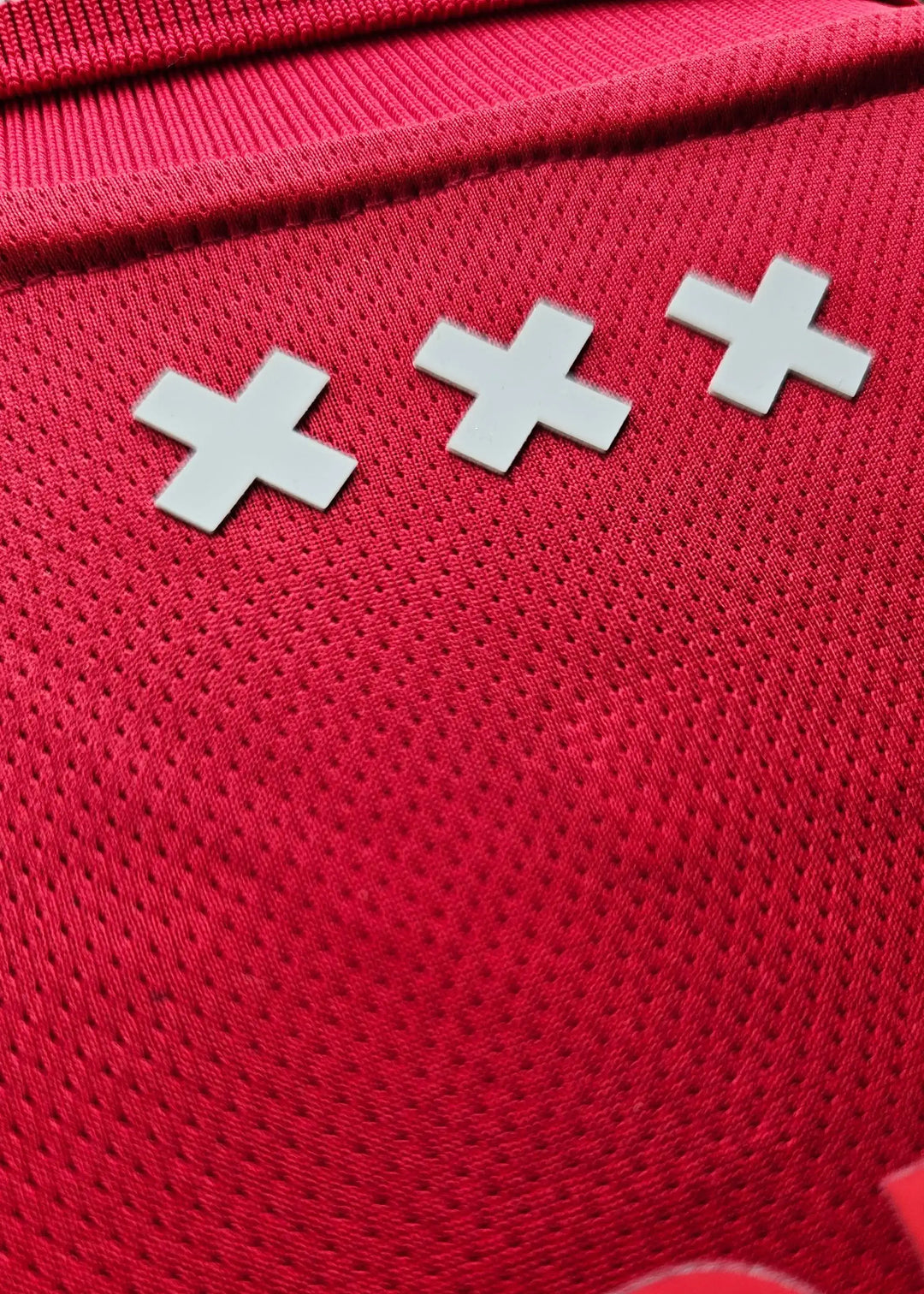Detail view showing three white crosses on a red background of the Ajax football shirt.