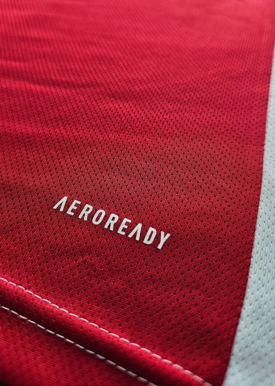 Close-up detail showing the word 'AEROREADY' on a red football shirt.