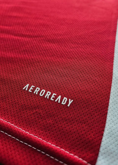 Close-up detail showing the word 'AEROREADY' on a red football shirt.