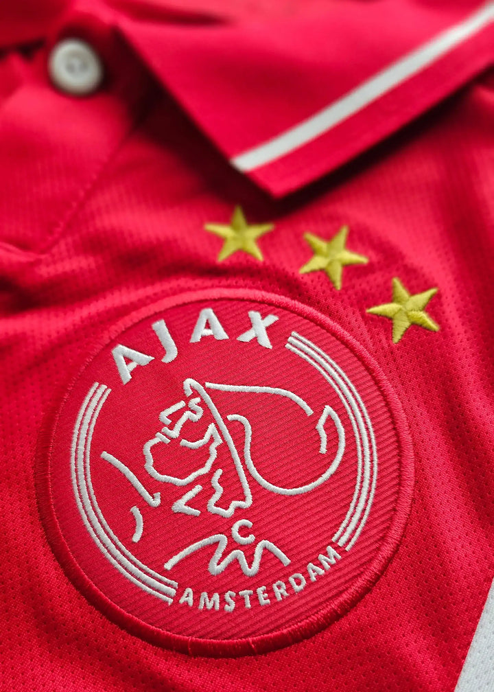 Close-up of the AFC Ajax crest with three stars on a red background.