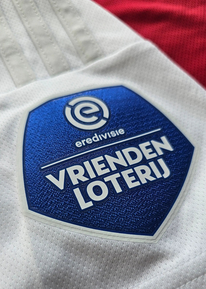 Crest detail featuring the Eredivisie logo and Vrienden Loterij on a white section of the football shirt.