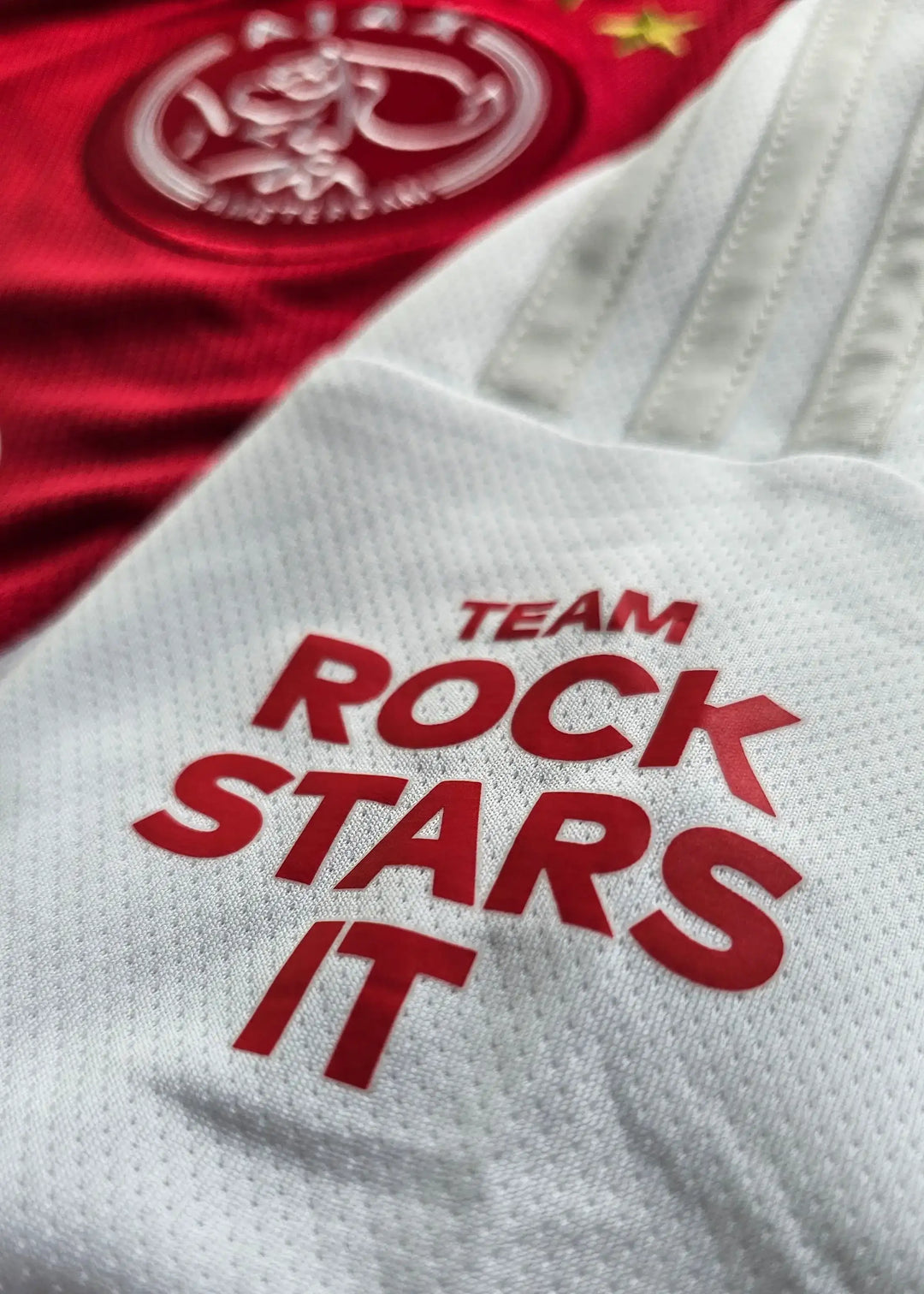 Crest detail featuring the AFC Ajax badge and the text 'TEAM ROCK STARS IT' in red.