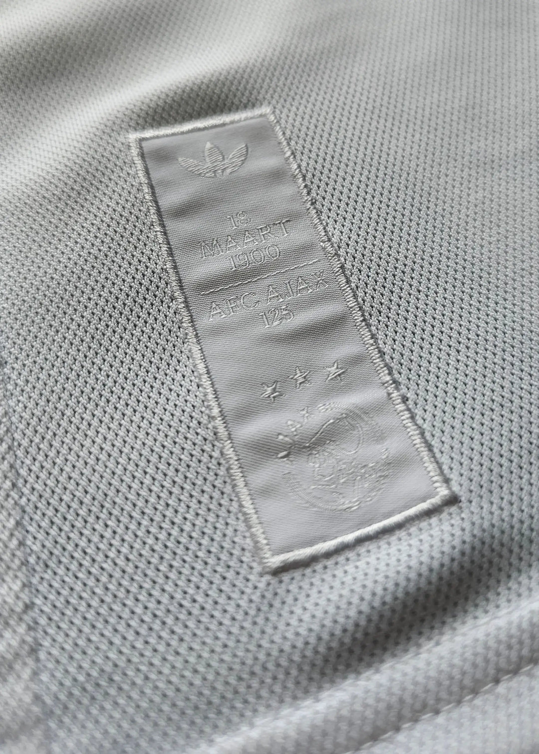 Crest detail featuring AFC Ajax 125th Anniversary text and three stars on the label.