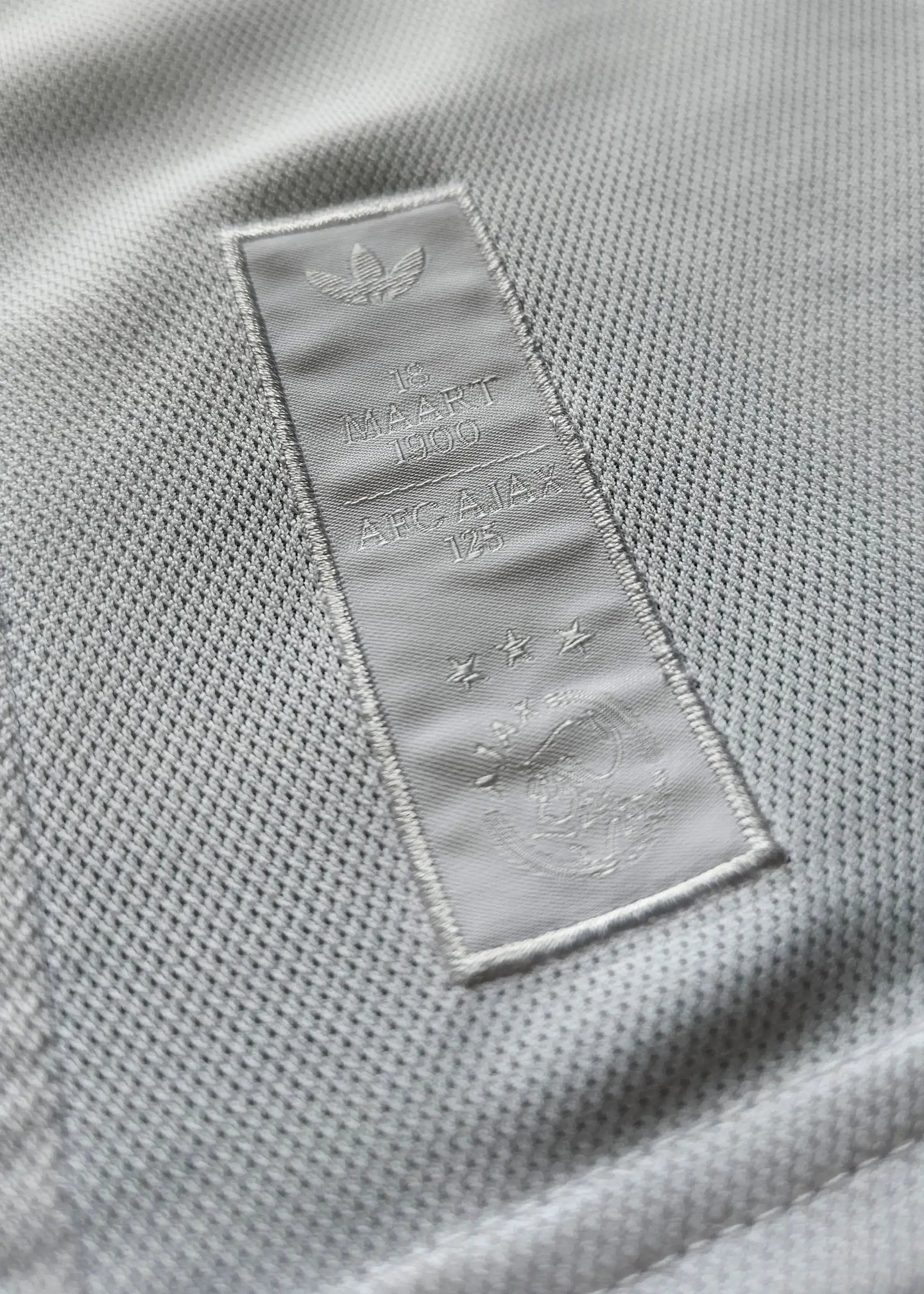 Crest detail featuring AFC Ajax 125th Anniversary text and three stars on the label.