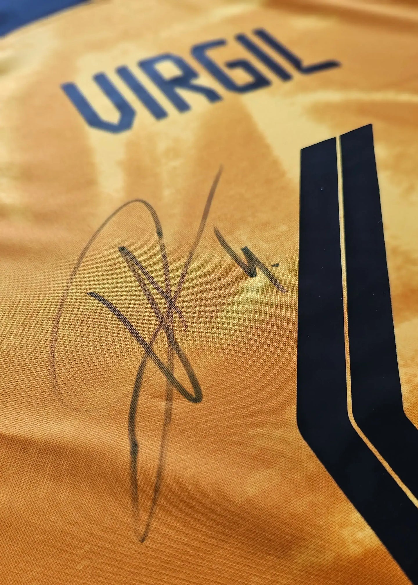 Close-up of the signature on Virgil van Dijk's Holland football shirt, featuring blue letters.