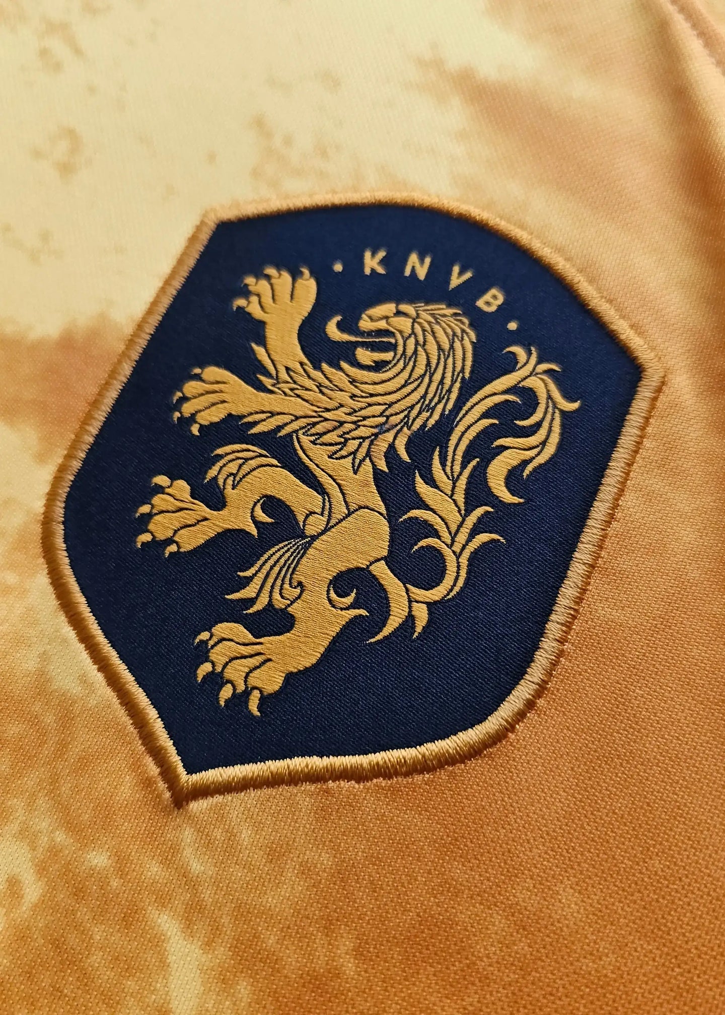 Crest detail featuring the KNVB logo and lion in gold on a navy background.