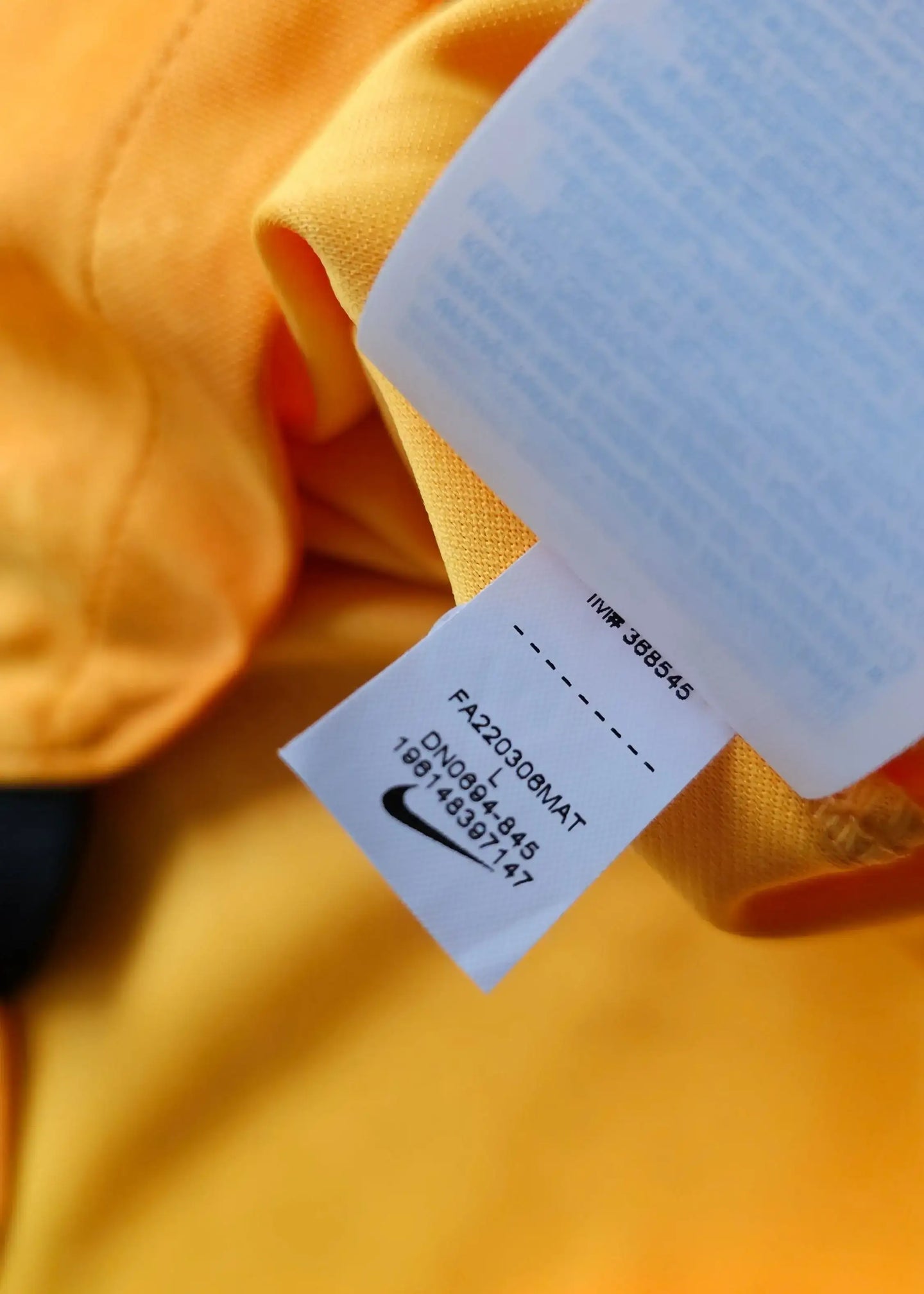 Care label displaying Nike branding and product details on an orange football shirt.
