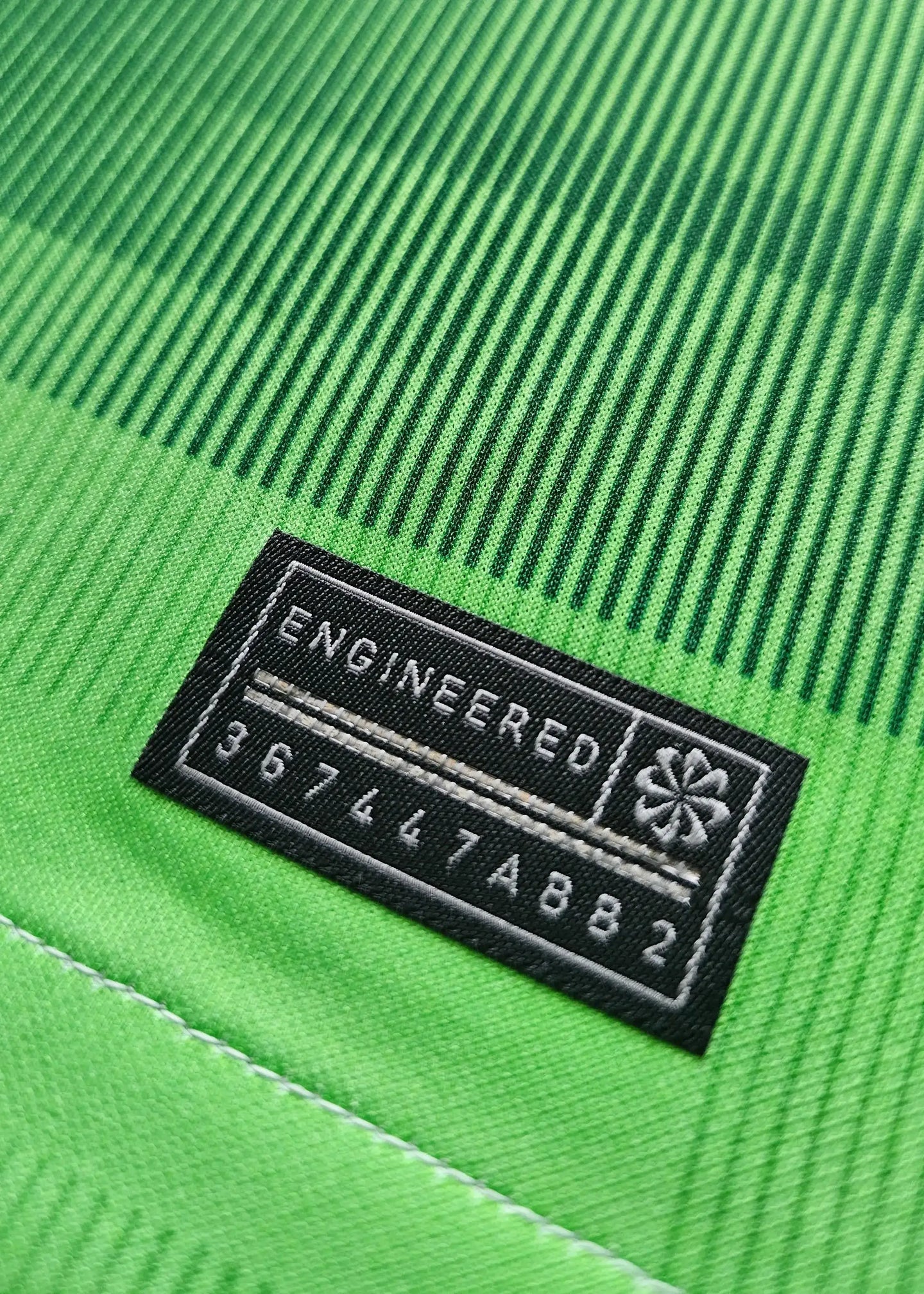 Engineered label with text and code 367447ABB2 on a green fabric background.