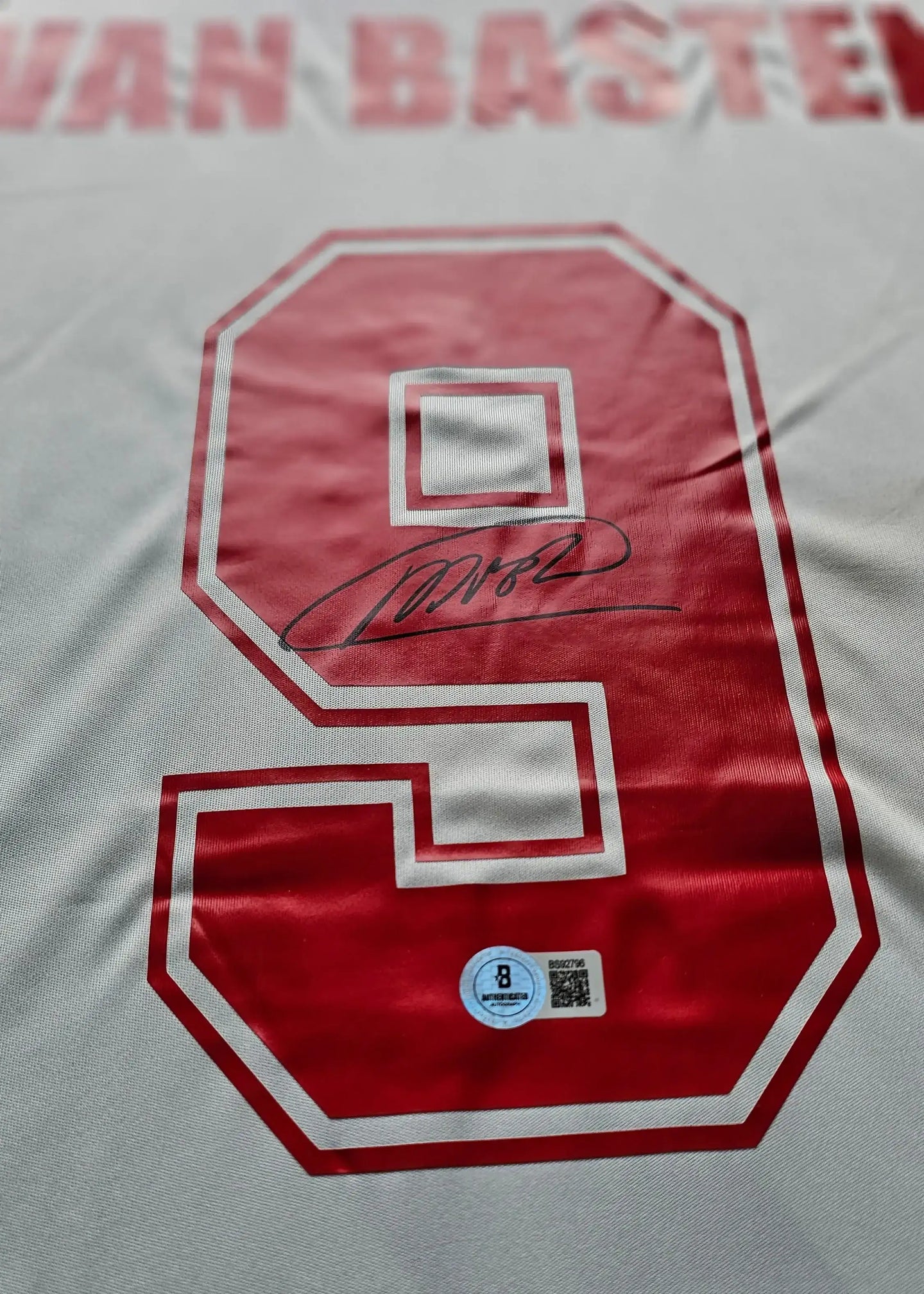 Detail view showing No. 9, signature, and name 'VAN BASTEN' in red on white football shirt.