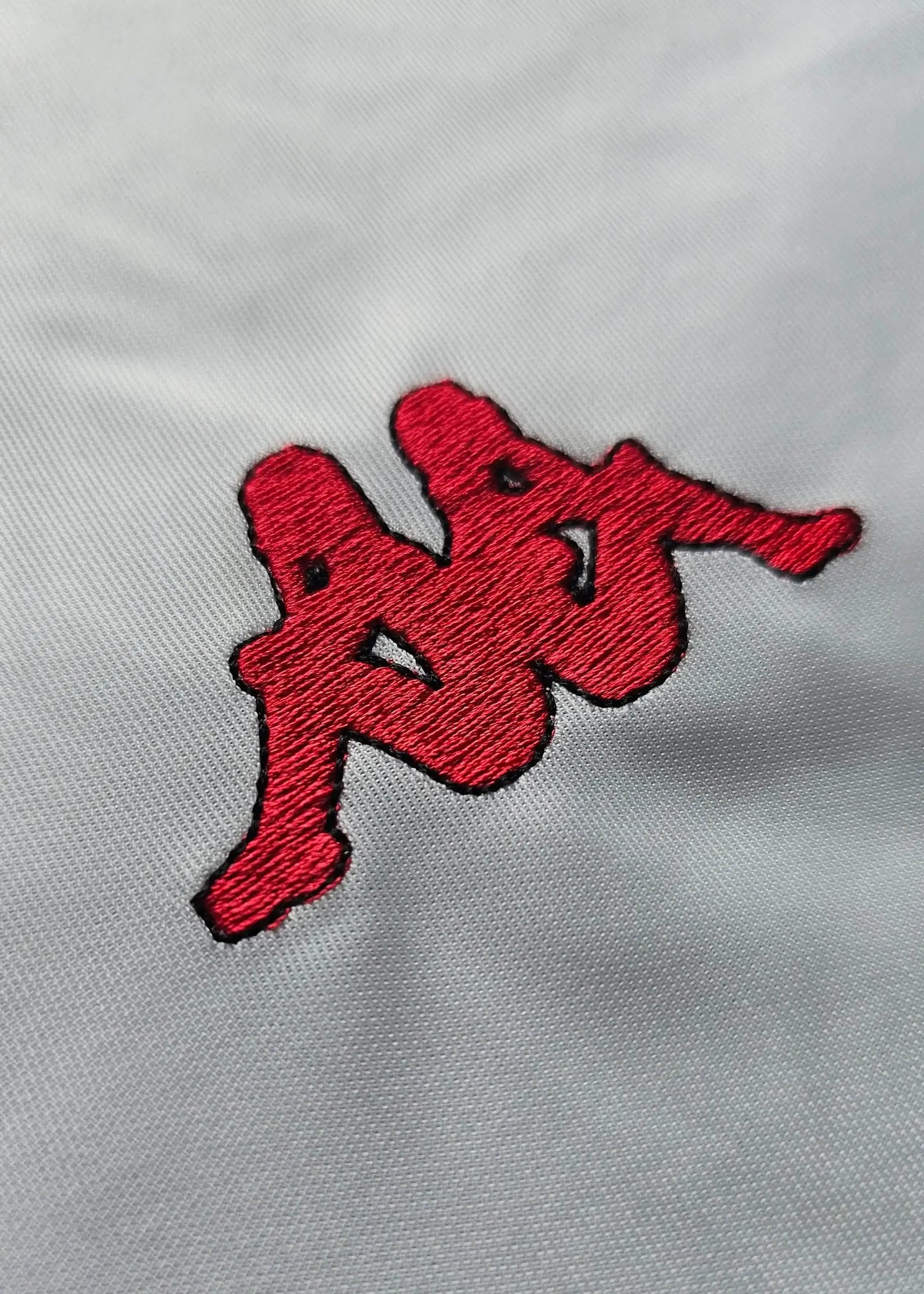 Close-up detail of the red embroidered Kappa logo on a white background.