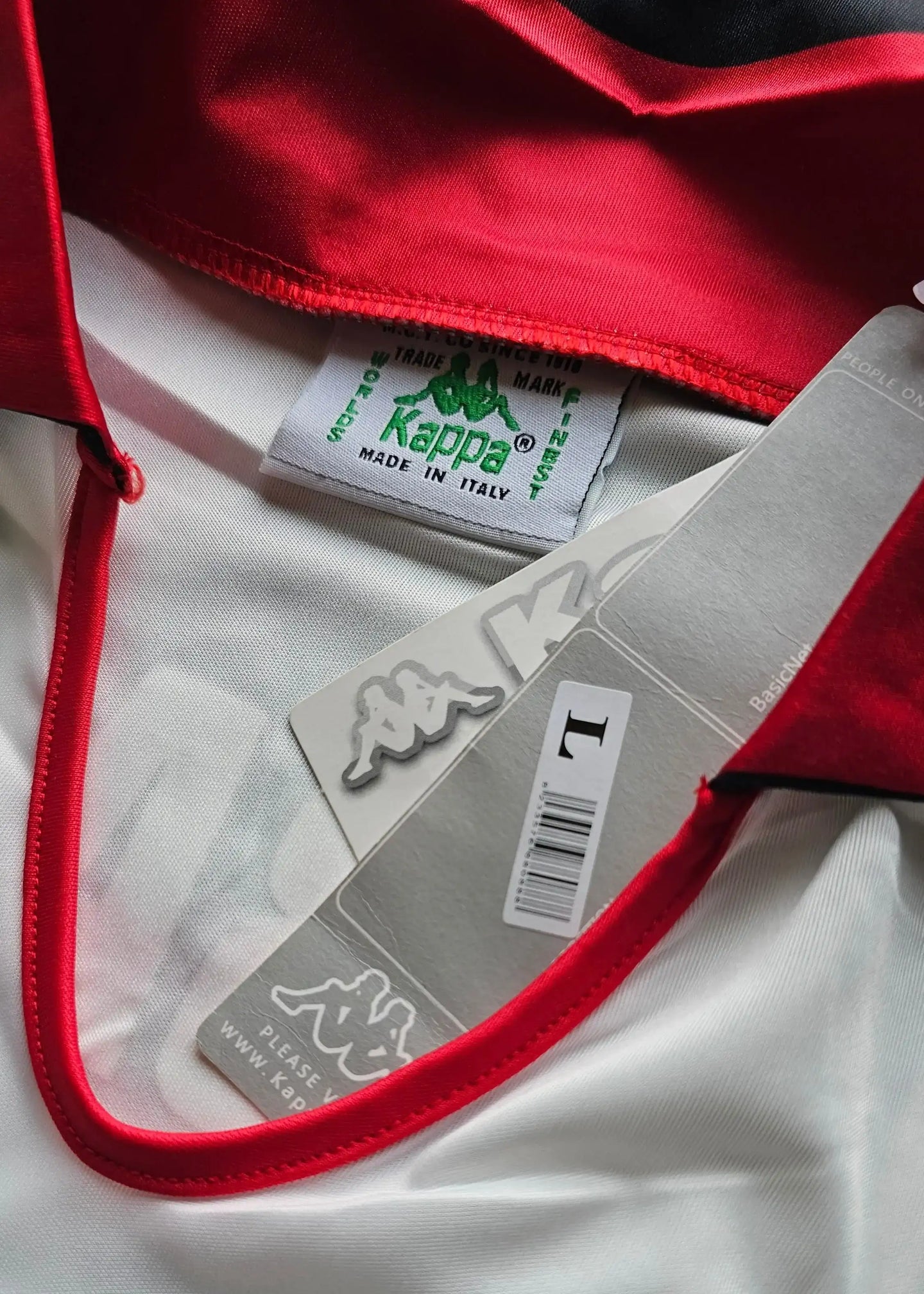 Detail showing red collar and Kappa brand label on white fabric with size tag visible.