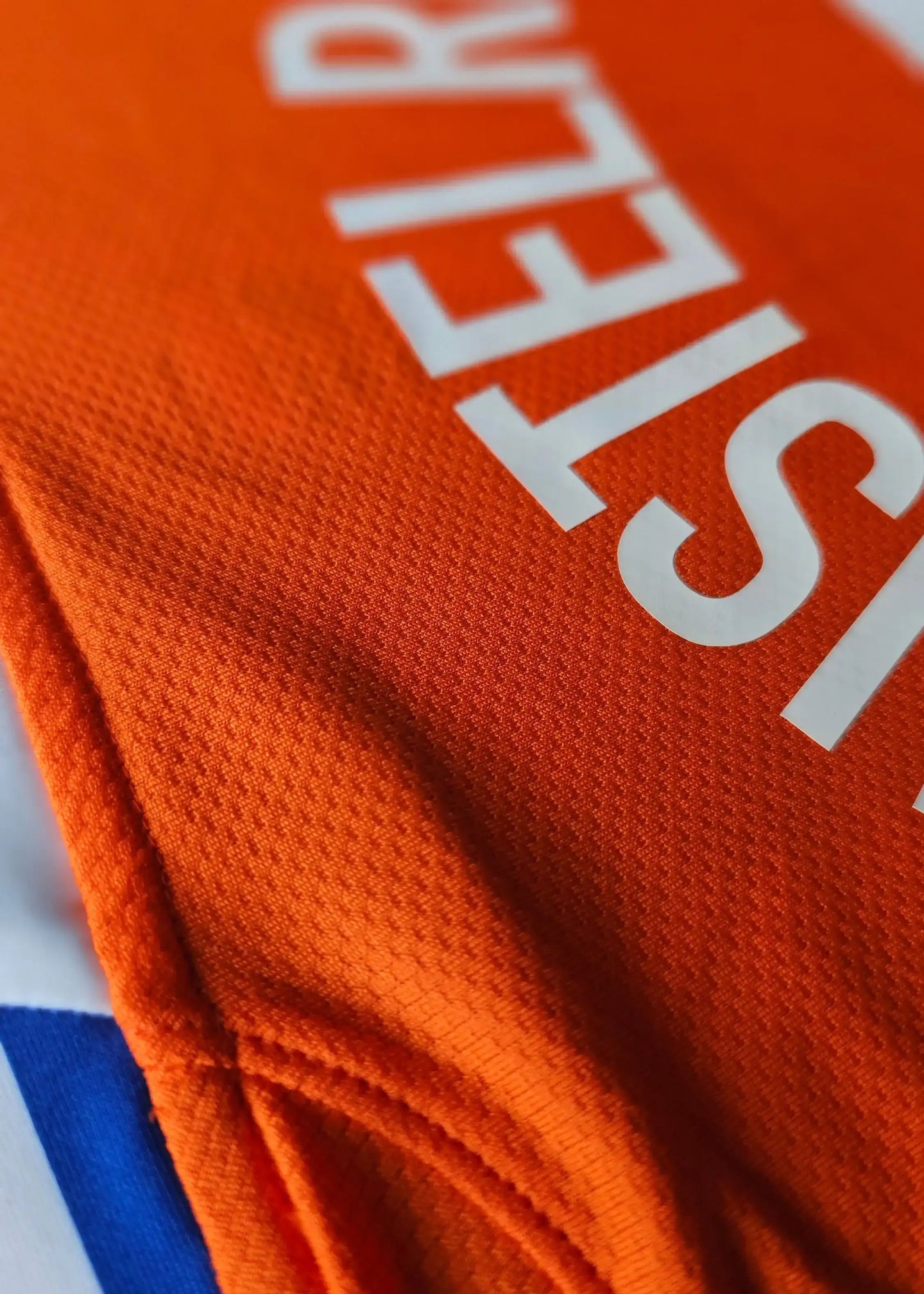 Close-up of Ruud van Nistelrooij's signed Holland football shirt showing vibrant orange fabric and visible 'STEL' text.
